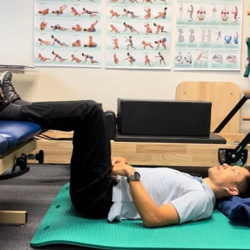 A person lying in supine position on back with legs up in 90 degrees of hip and knee flexion