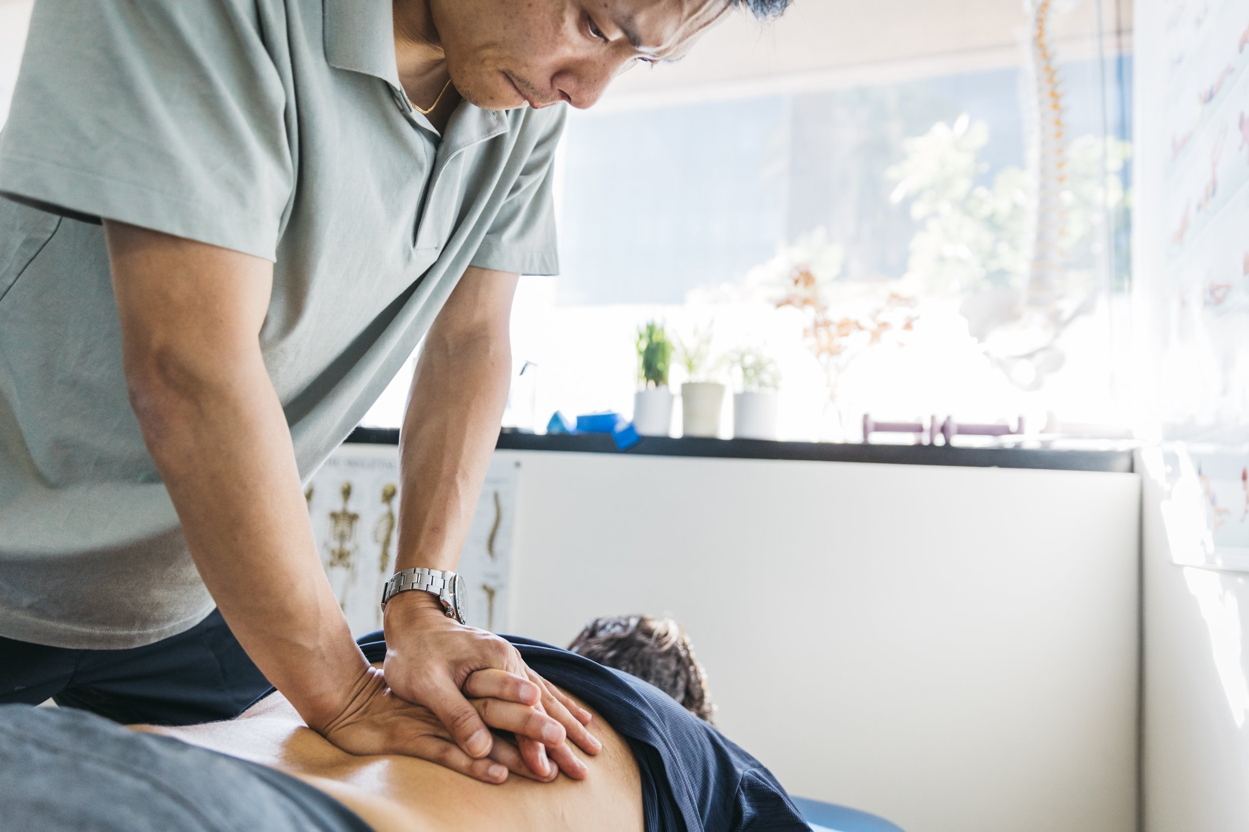 A physical therapist showing the overhead squatting movement to a patient during an initial evaluation as the patient mimics the movement and demonstrates his movements.
