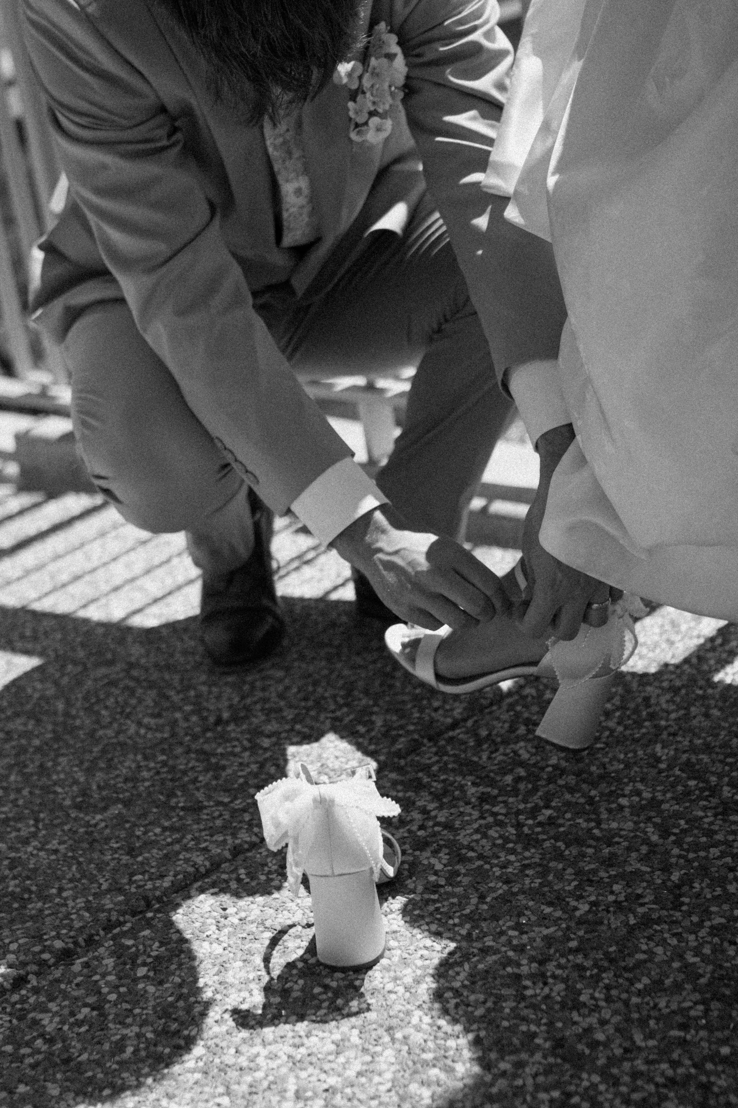 Groom helping bride put her heel on