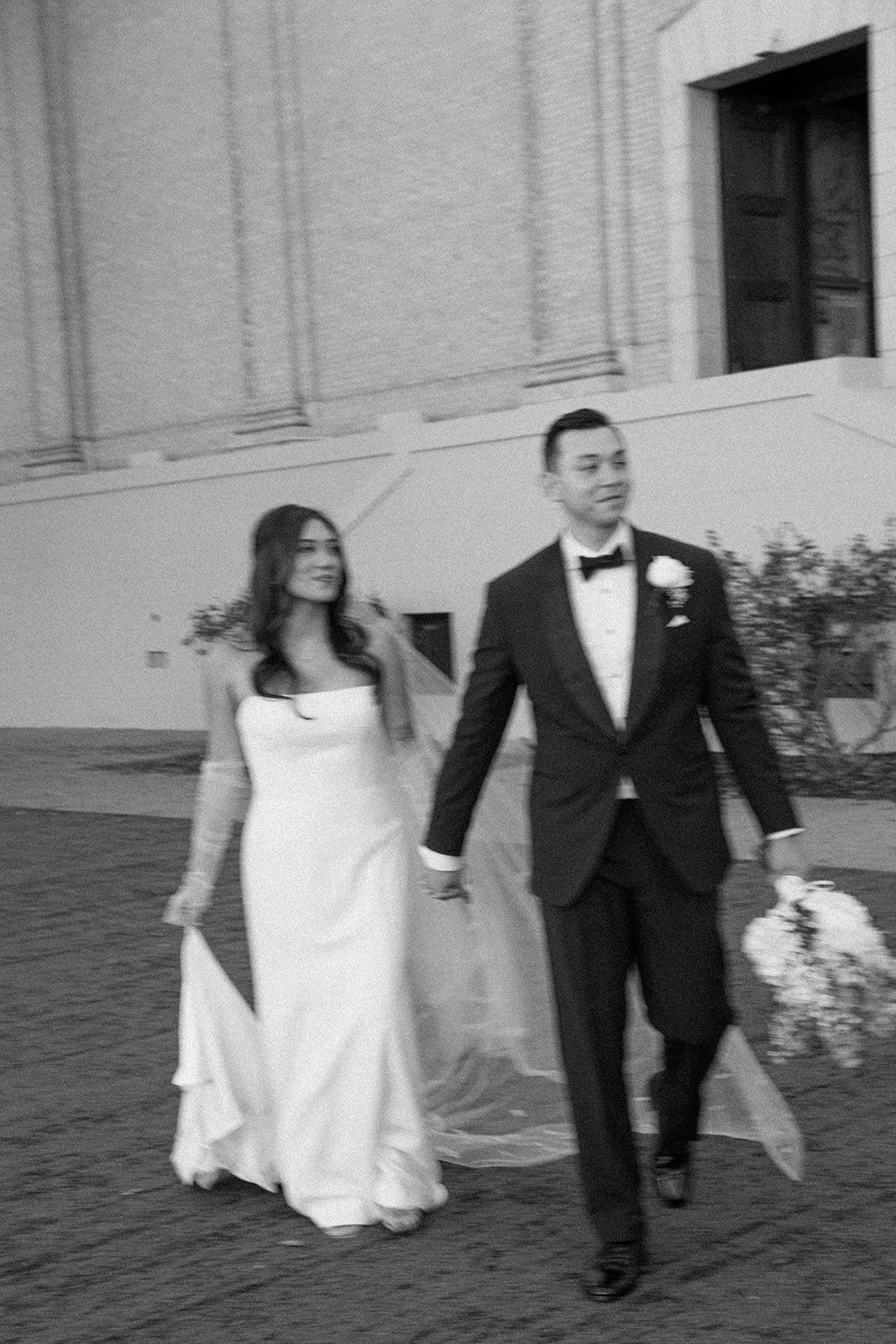 A black and white photo of a bride and groom walking away from their church wedding