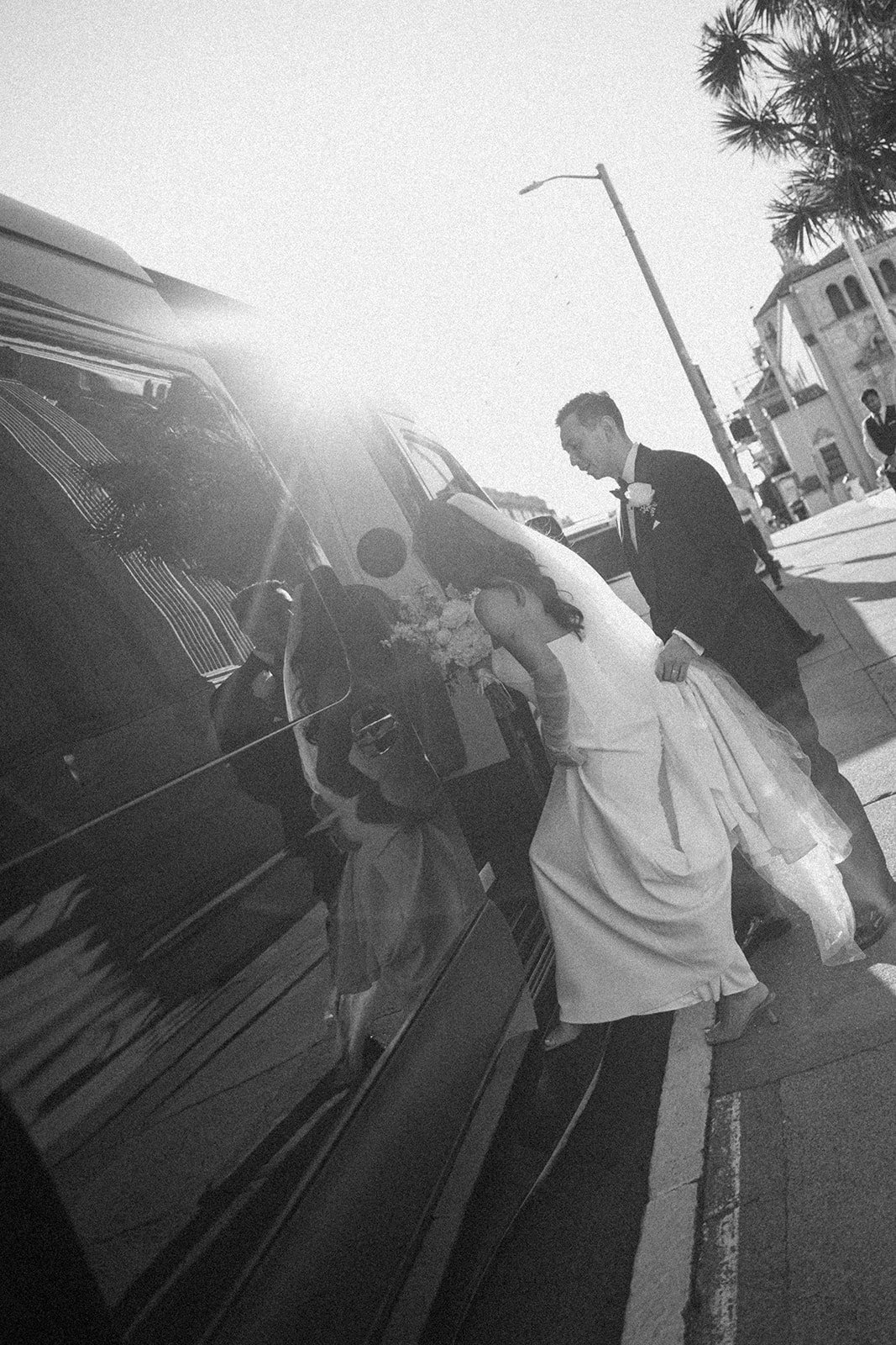 A bride and groom following their day of wedding timeline getting in the car to ride to the reception