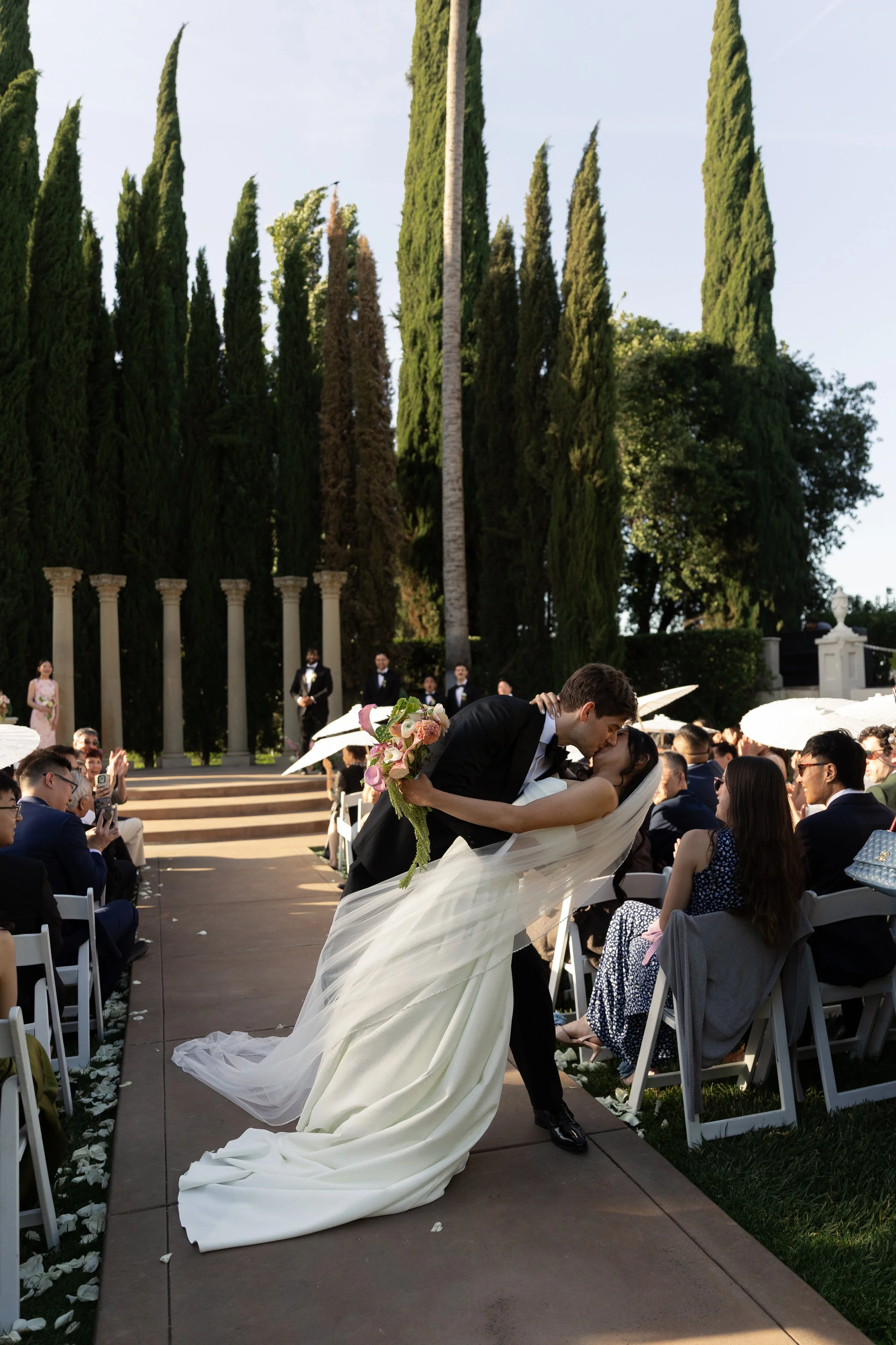 bride and groom share a kiss at the end of the aisle