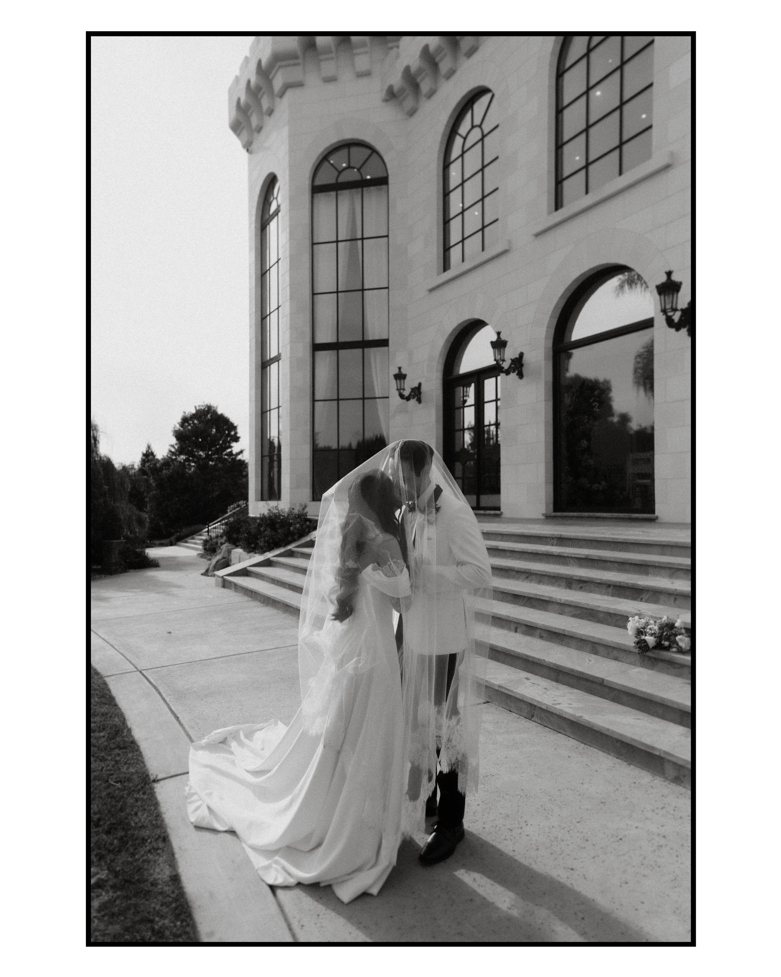 bride and groom cuddled under veil during sunset