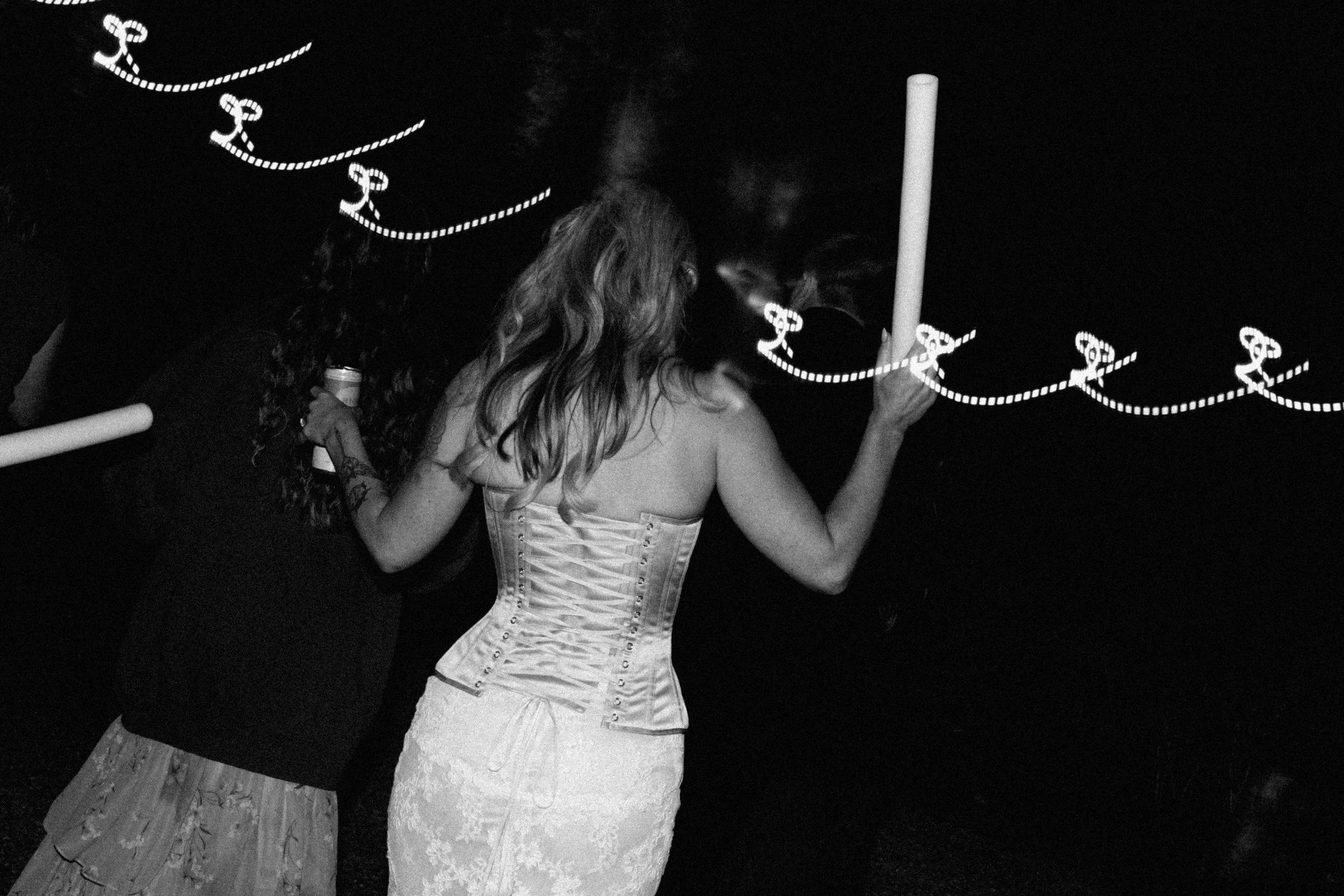 A black and white candid photo of a bride dancing at her wedding reception