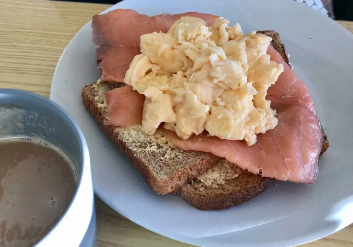 Scrambled eggs on smoked salmon and toast with a cup of coffee.