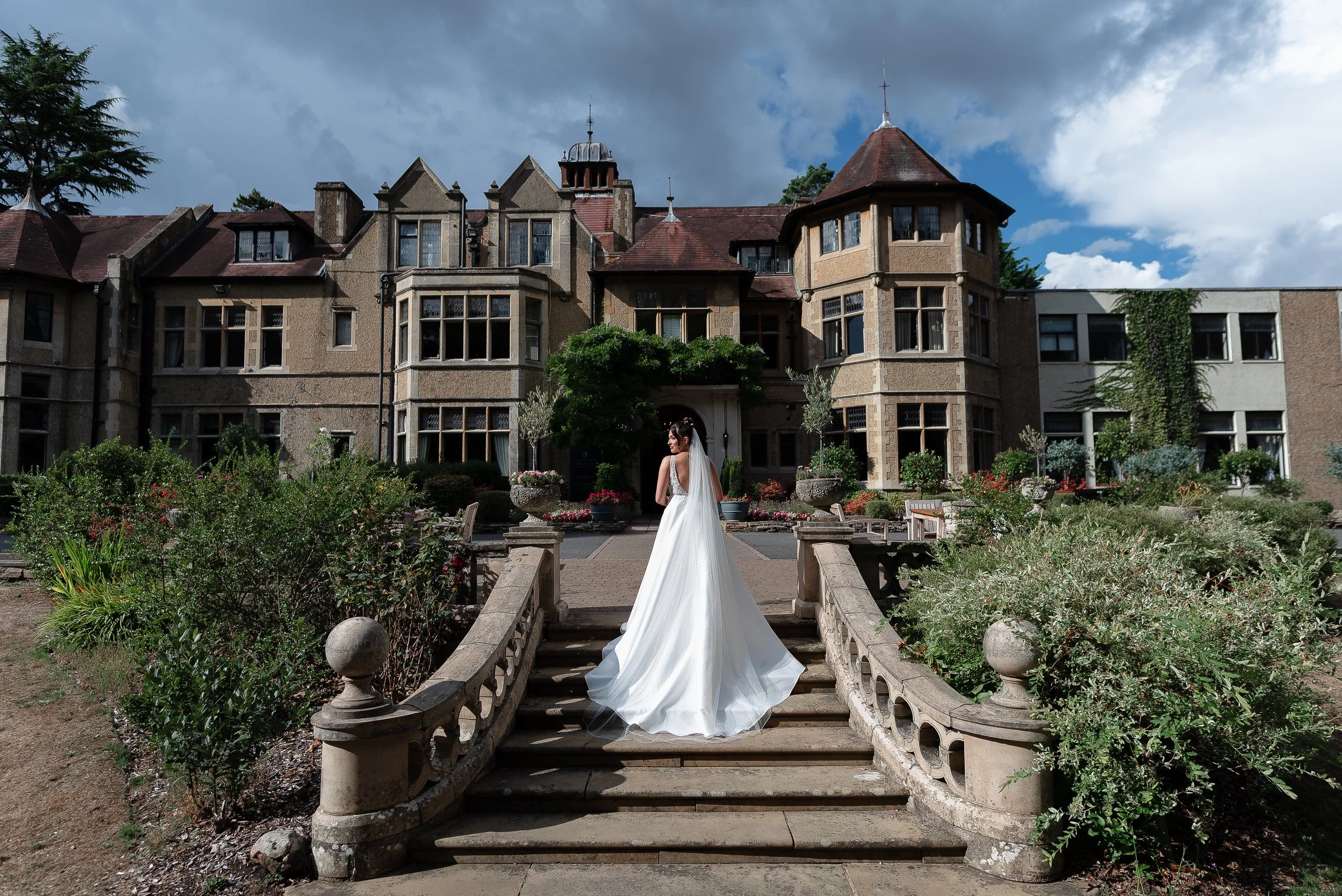 Beautiful bride standing on the steps in front of Frimley Hall hotel taken by Paul Stickland Wedding Photography a Hampshire wedding photographer
