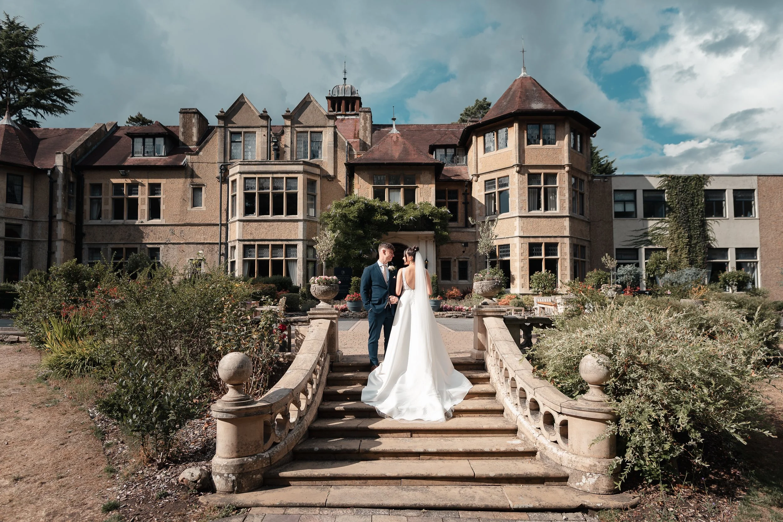 Bride and groom embracing on the garden steps outside Frimley Hall Hotel after their ceremony looking into each others eyes