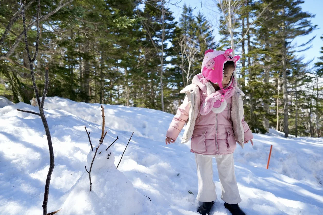 Child searching for easter eggs in the snow.