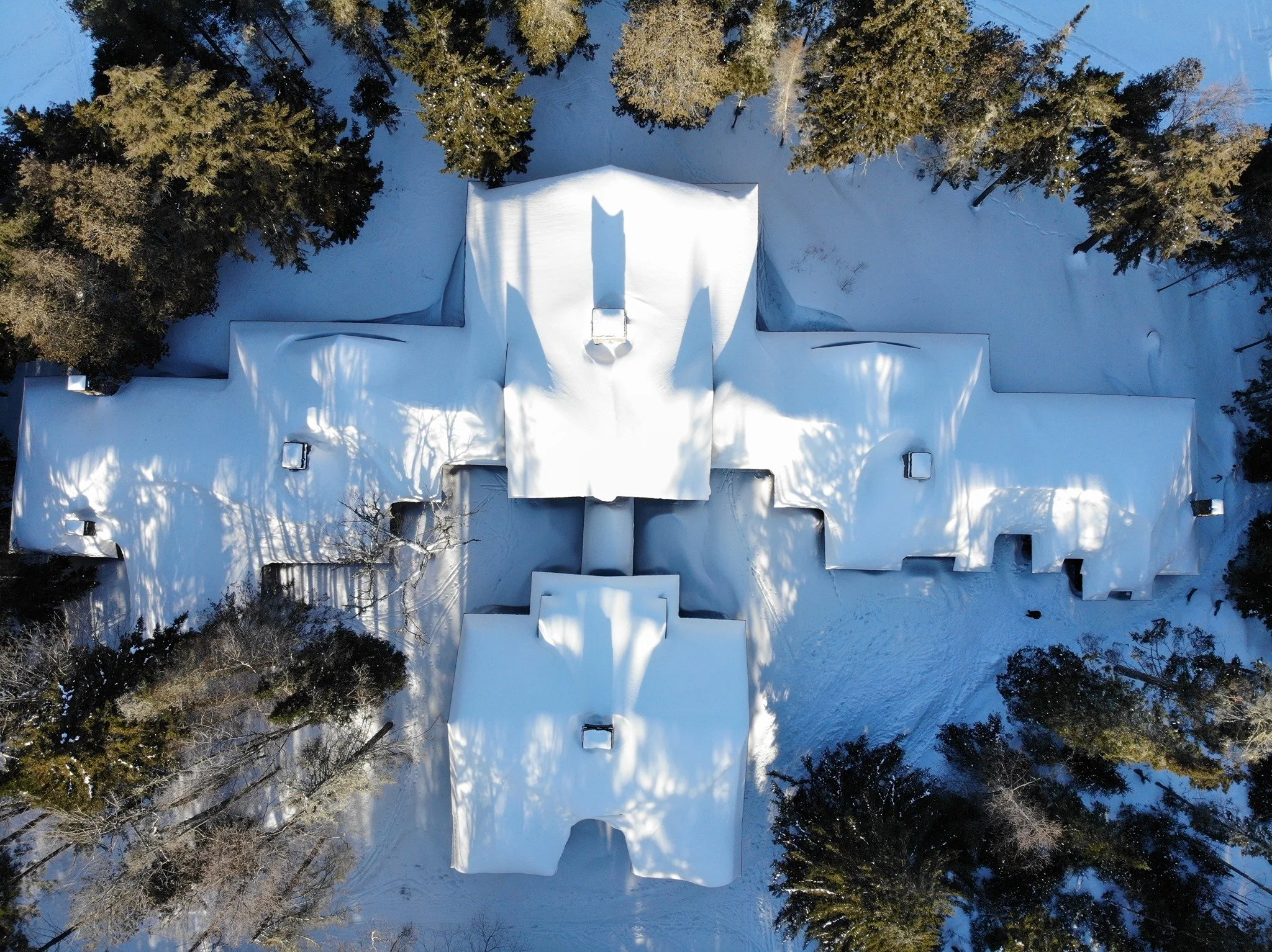 Aerial photo of Great Camp Santanoni's main lodge covered in snow in winter.
