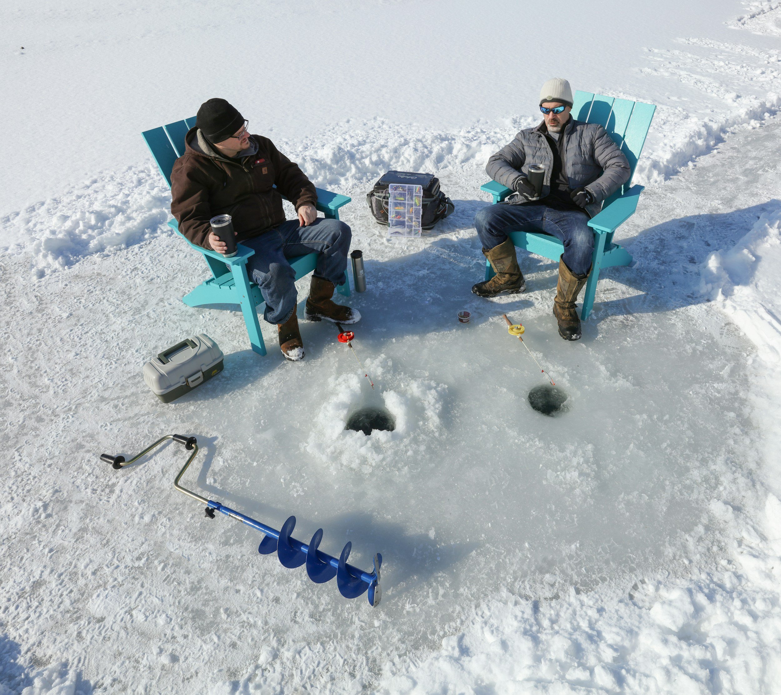 Two men compete in ice fishing derby in Adirondack chairs.