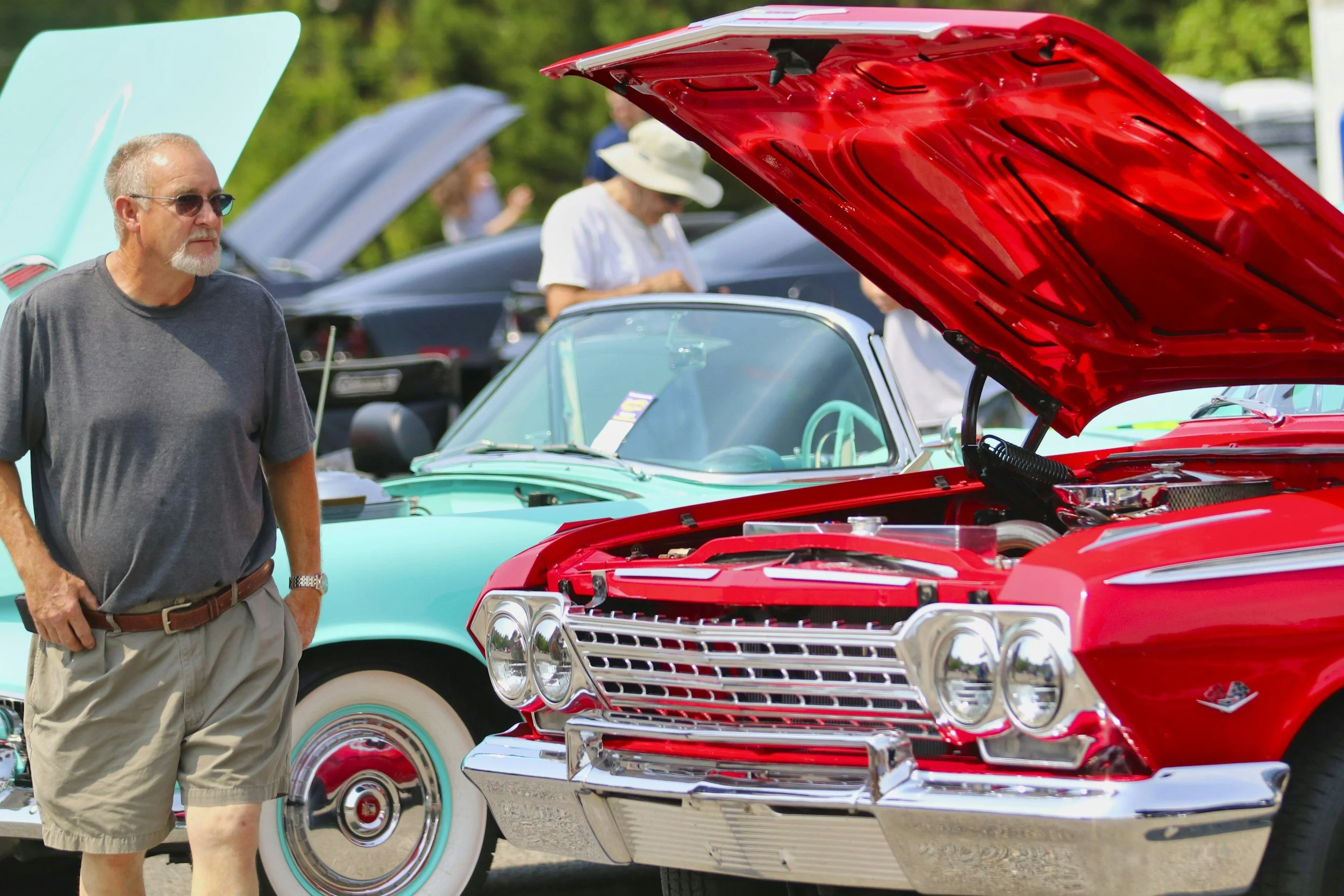 Man admiring antique and vintage cars at a Fathers' Day car show in the Adirondacks.