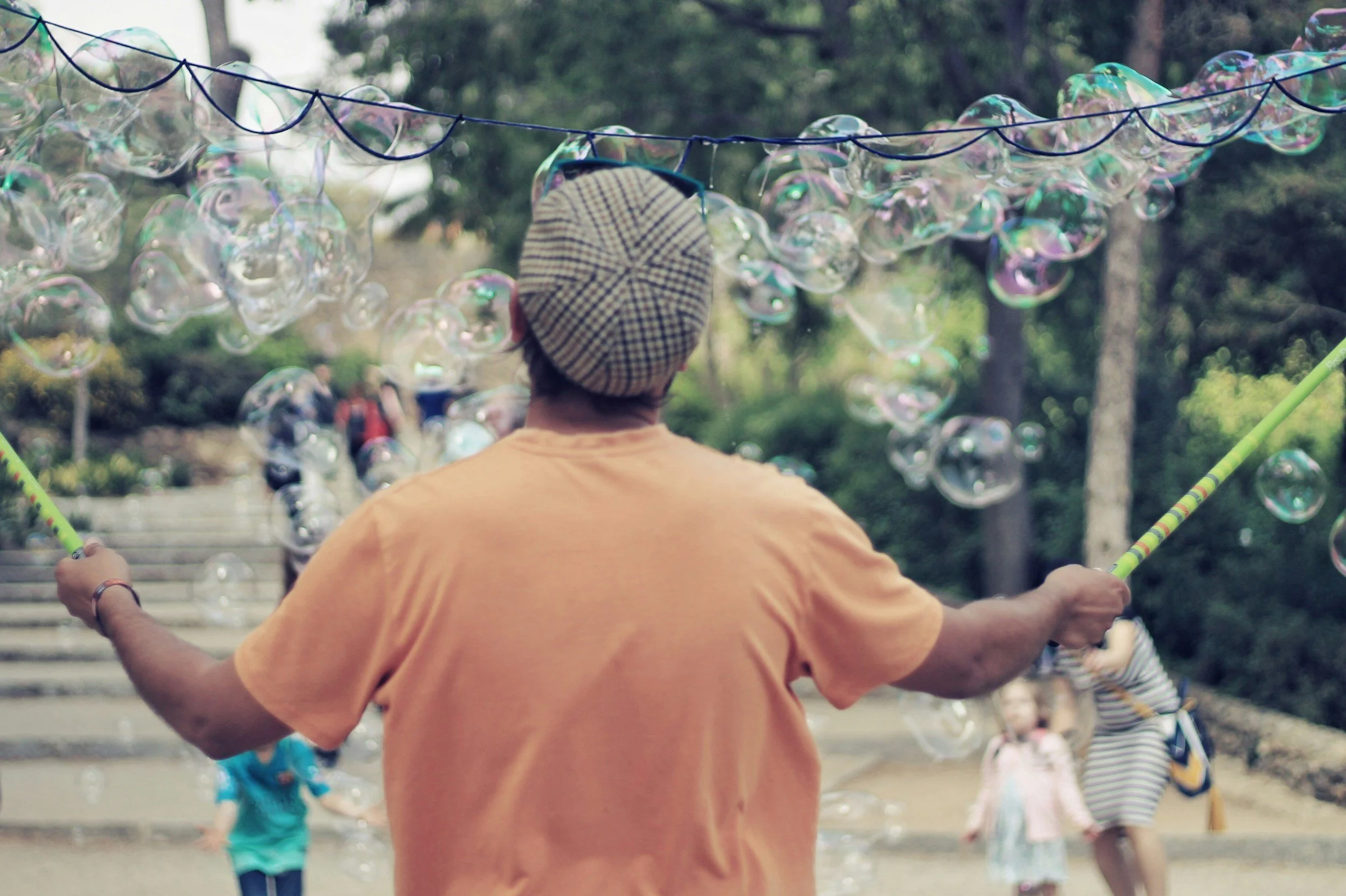 Man blowing soap bubbles as children look on