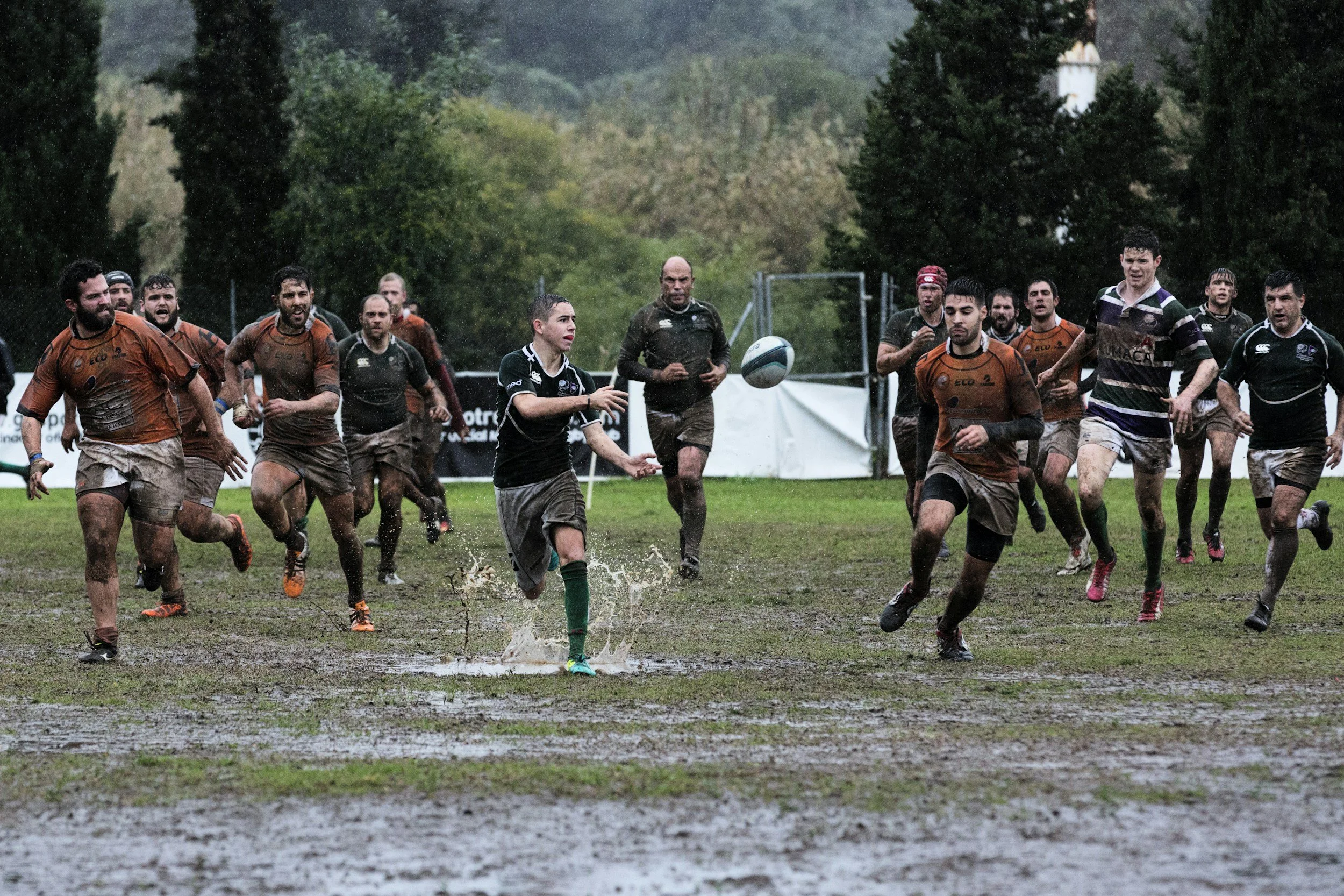 Men playing rugby in a muddy field like in the CanAm tournament in the Adirondacks.