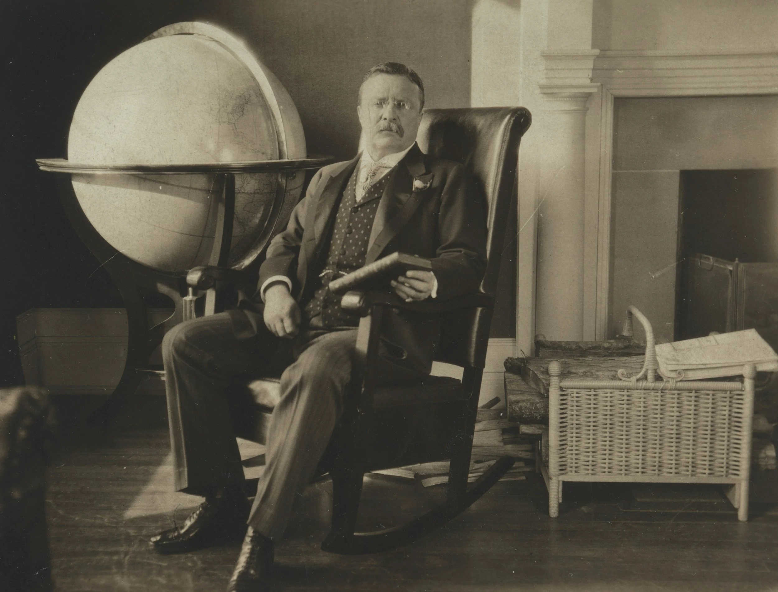 President Theodore "Teddy" Roosevelt in his library holding one of him many books.