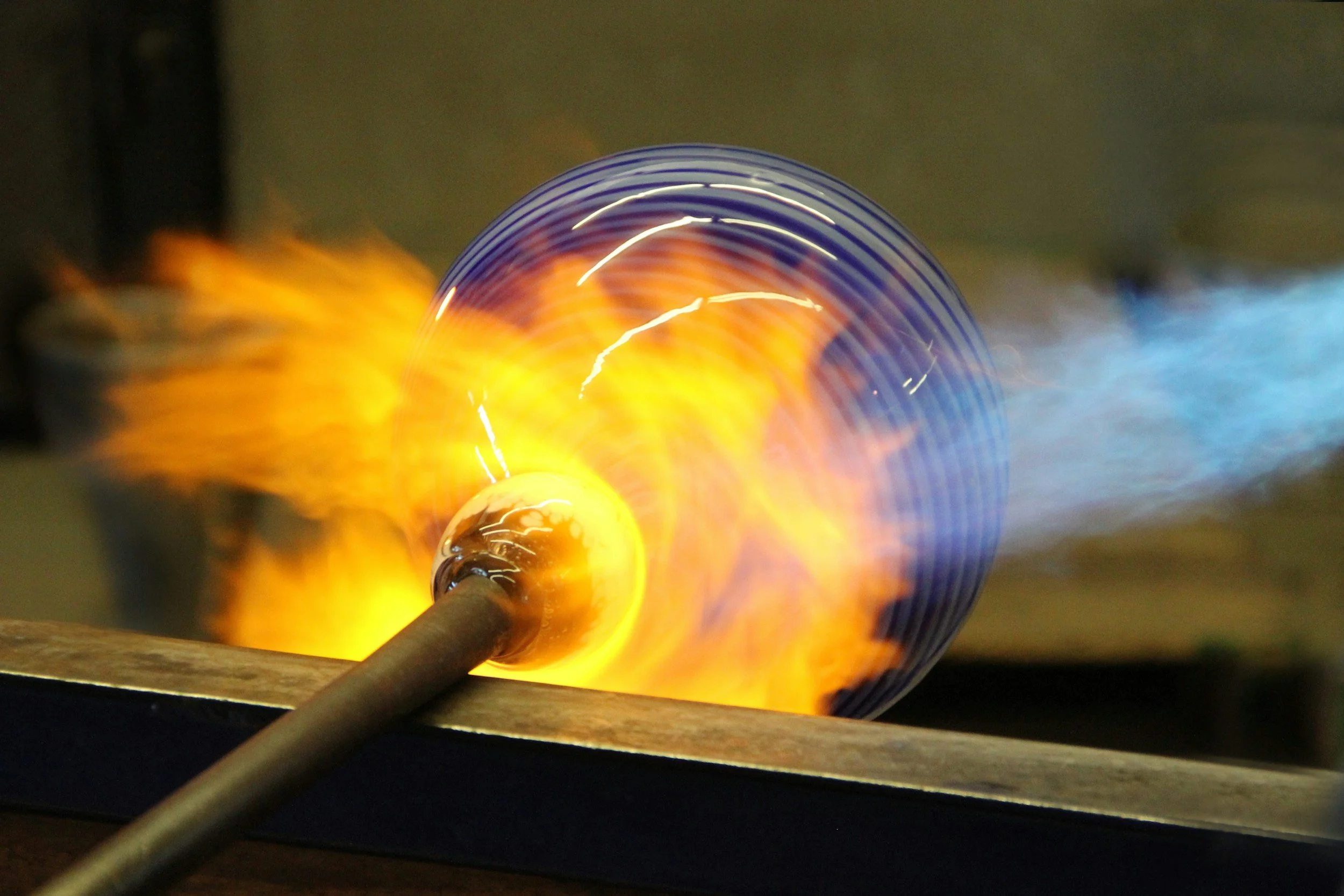 Glassblower making a vase from molten glass.