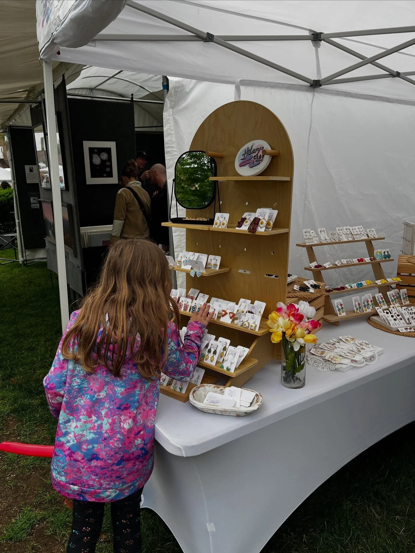 Girl admiring hand-crafted jewelry in Glens Falls City Park.