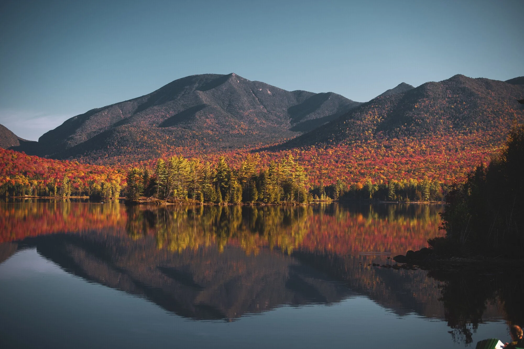 Dix Mountain with peak fall foliage reflected in Elk Lake.