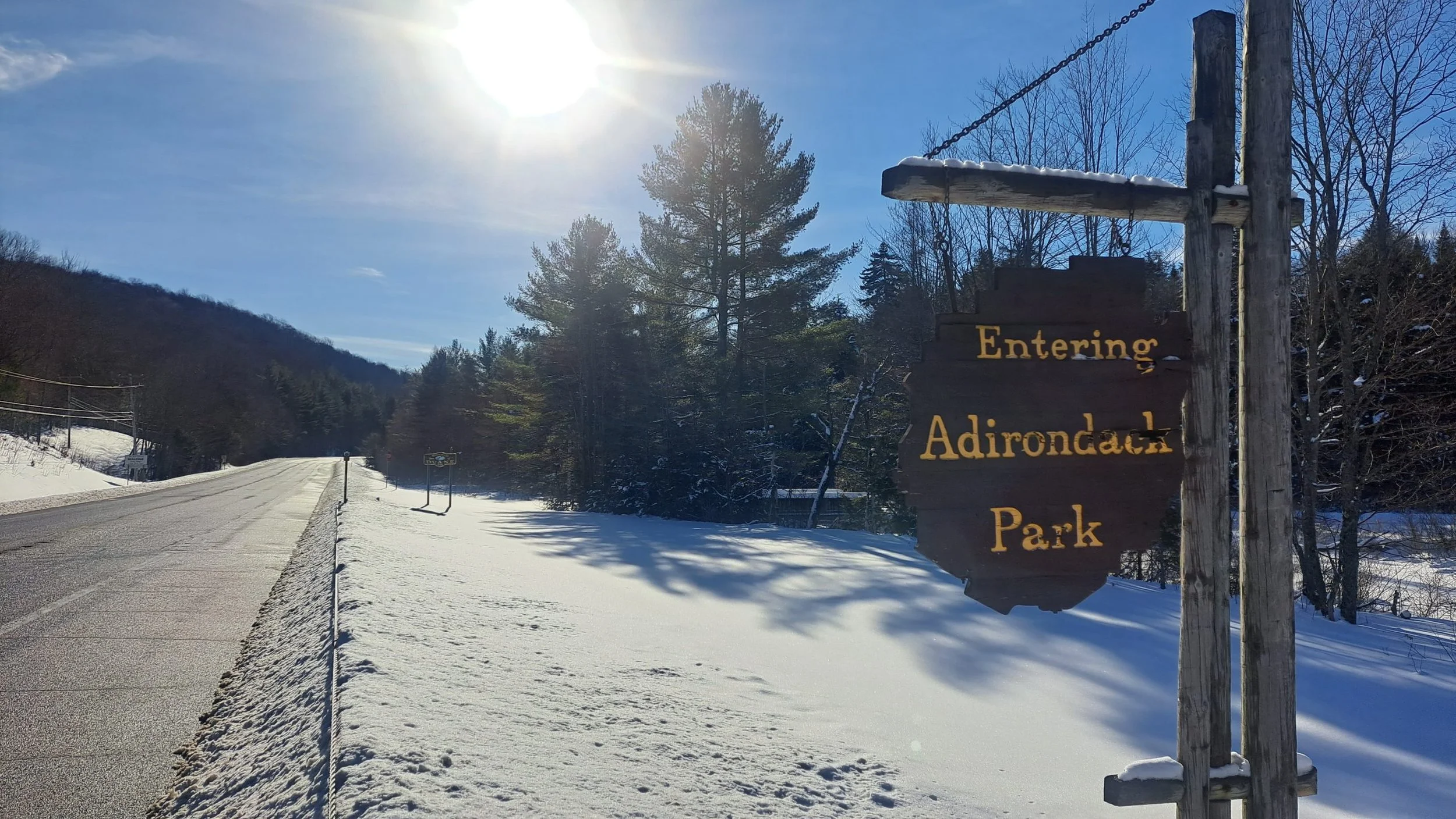 Sign welcoming visitors to the Adirondack Park on a sunny winter day.