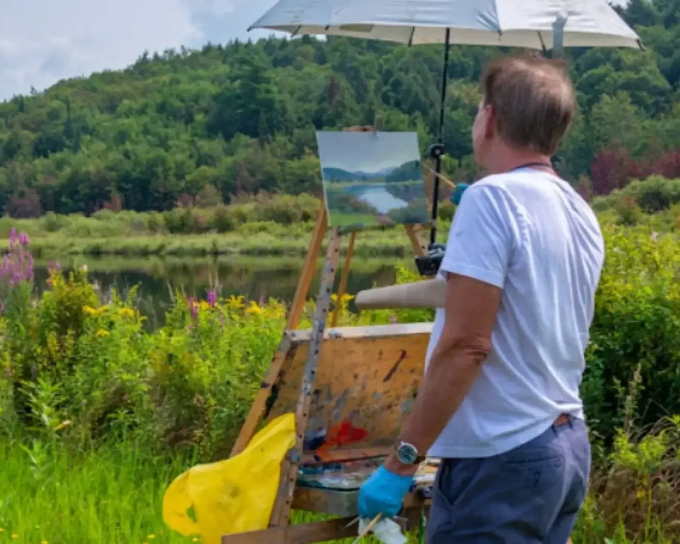 Man painting an outdoor scene in Saranac Lake at the Adirondack Plein Air Festival.