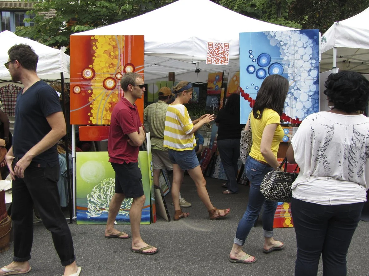 Paintings on exhibit at an arts festival.