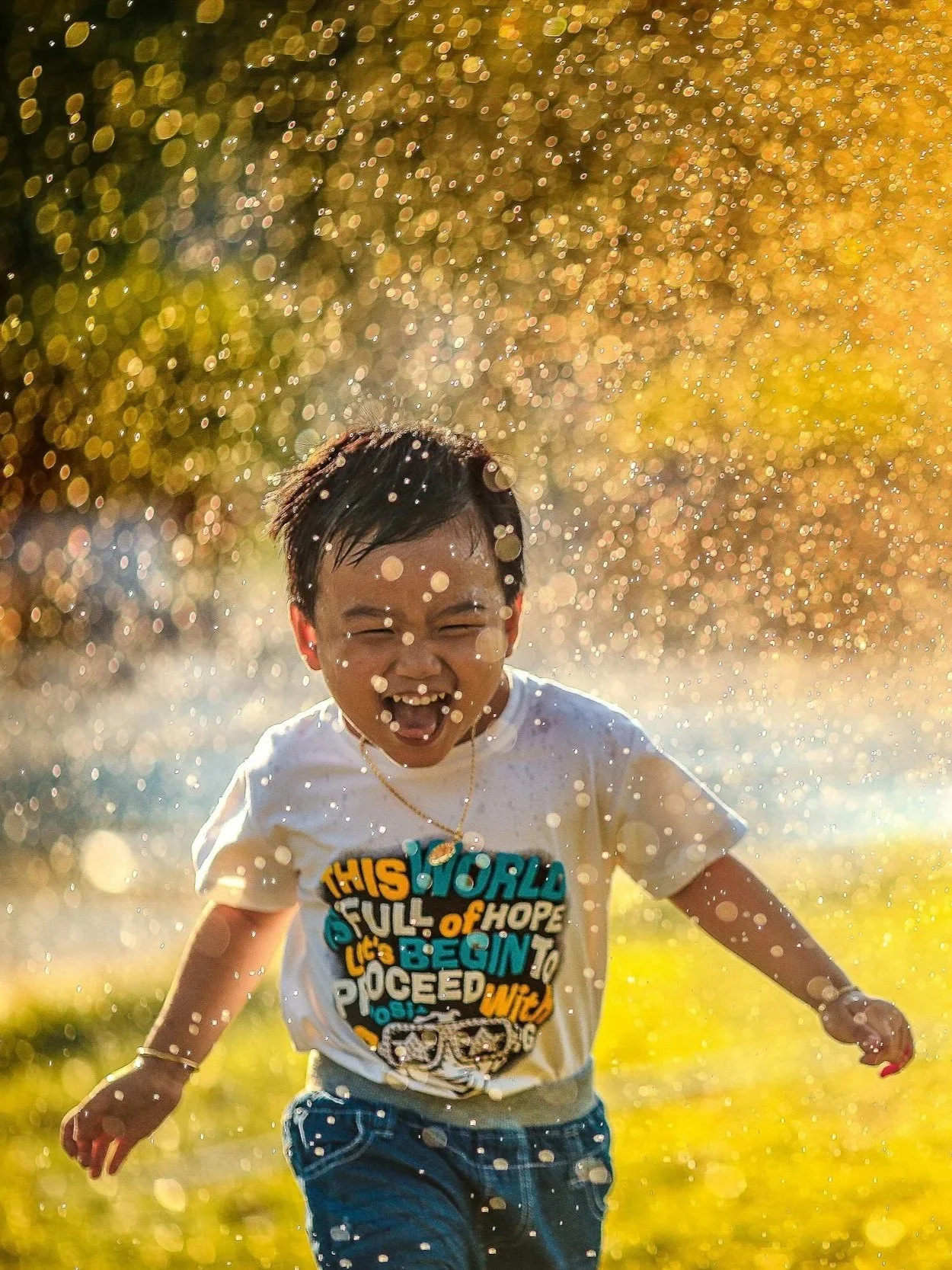 Young boy splaying in sprinkler in the summer.