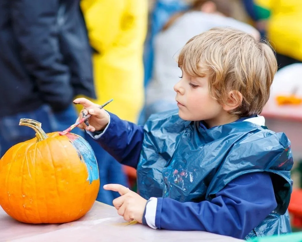 Child painting a pumpkin at the ADKX Fall Festival on Blue Mountain Lake.