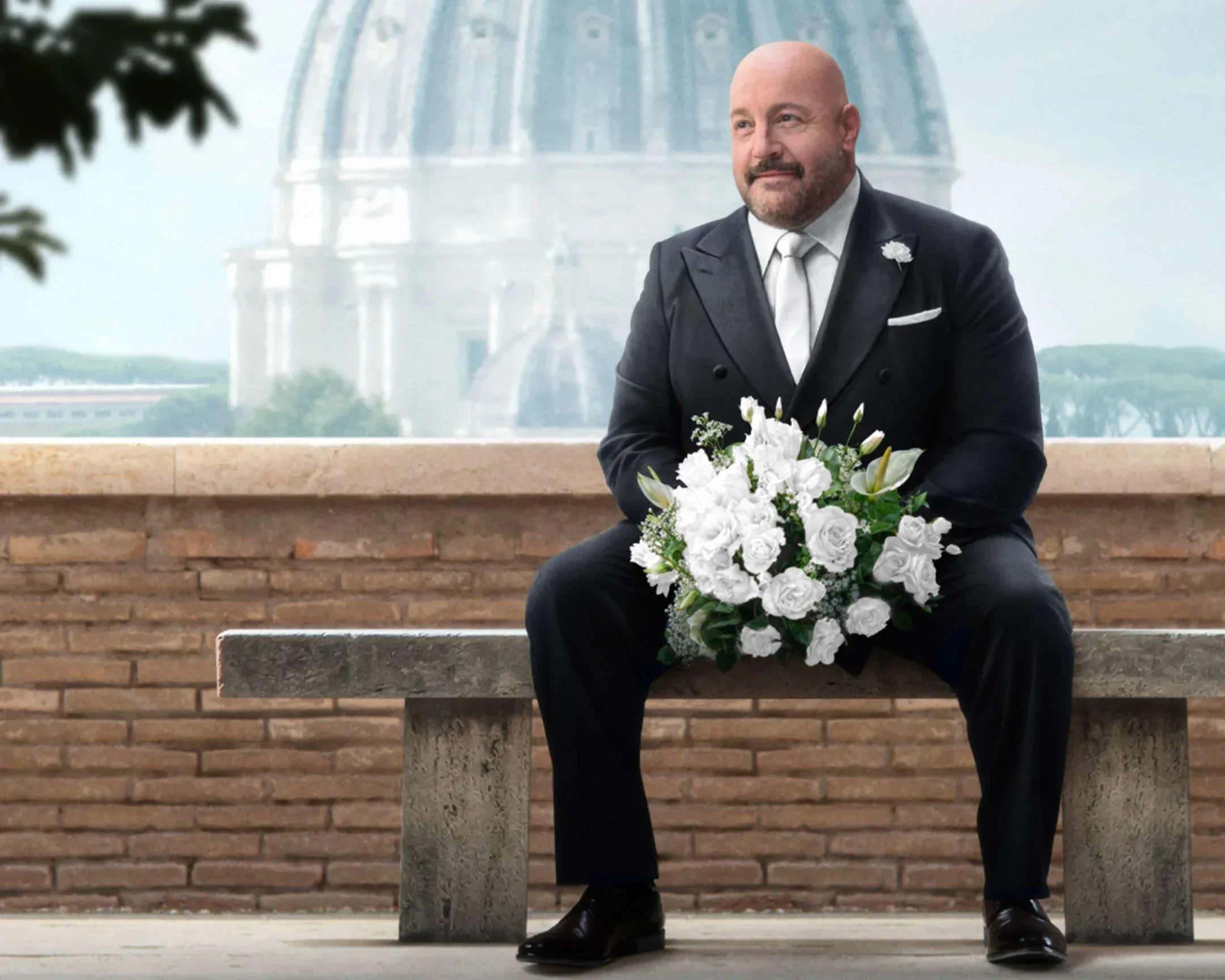 Photo of Kevin James sitting on a bench in Rome in the movie Solo Mio.