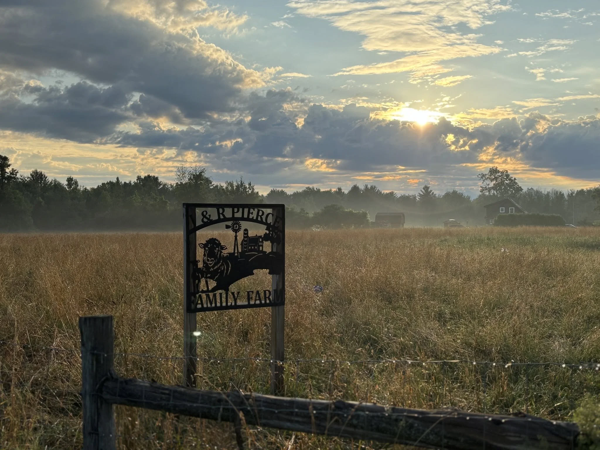J&R Pierce Family Farm sign overlooking pasture at sunset in West Chazy, New York.