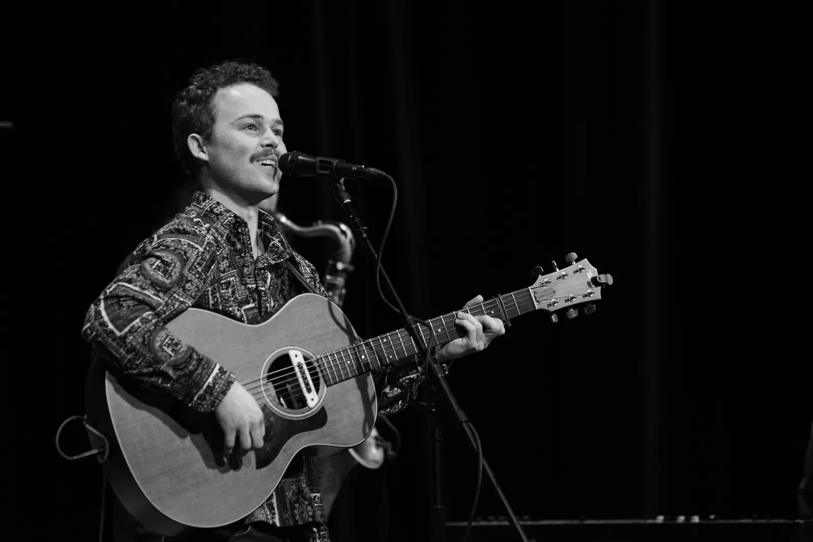 Reese Fulmer singing and playing guitar in a live performance.