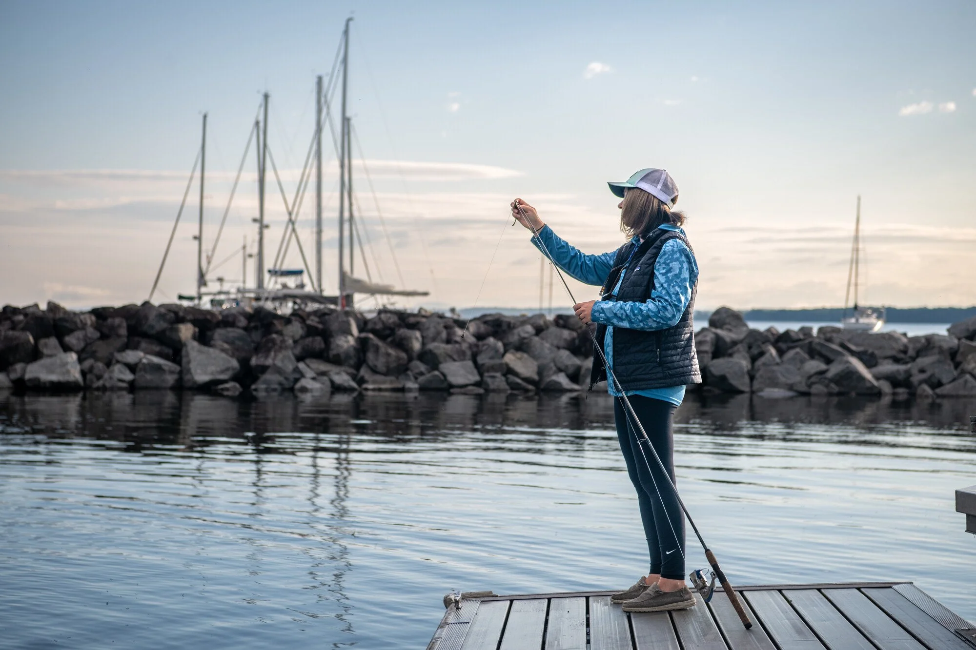 Woman preparing to fish off a dock on Lake Champlain in New York State's Adirondack park.