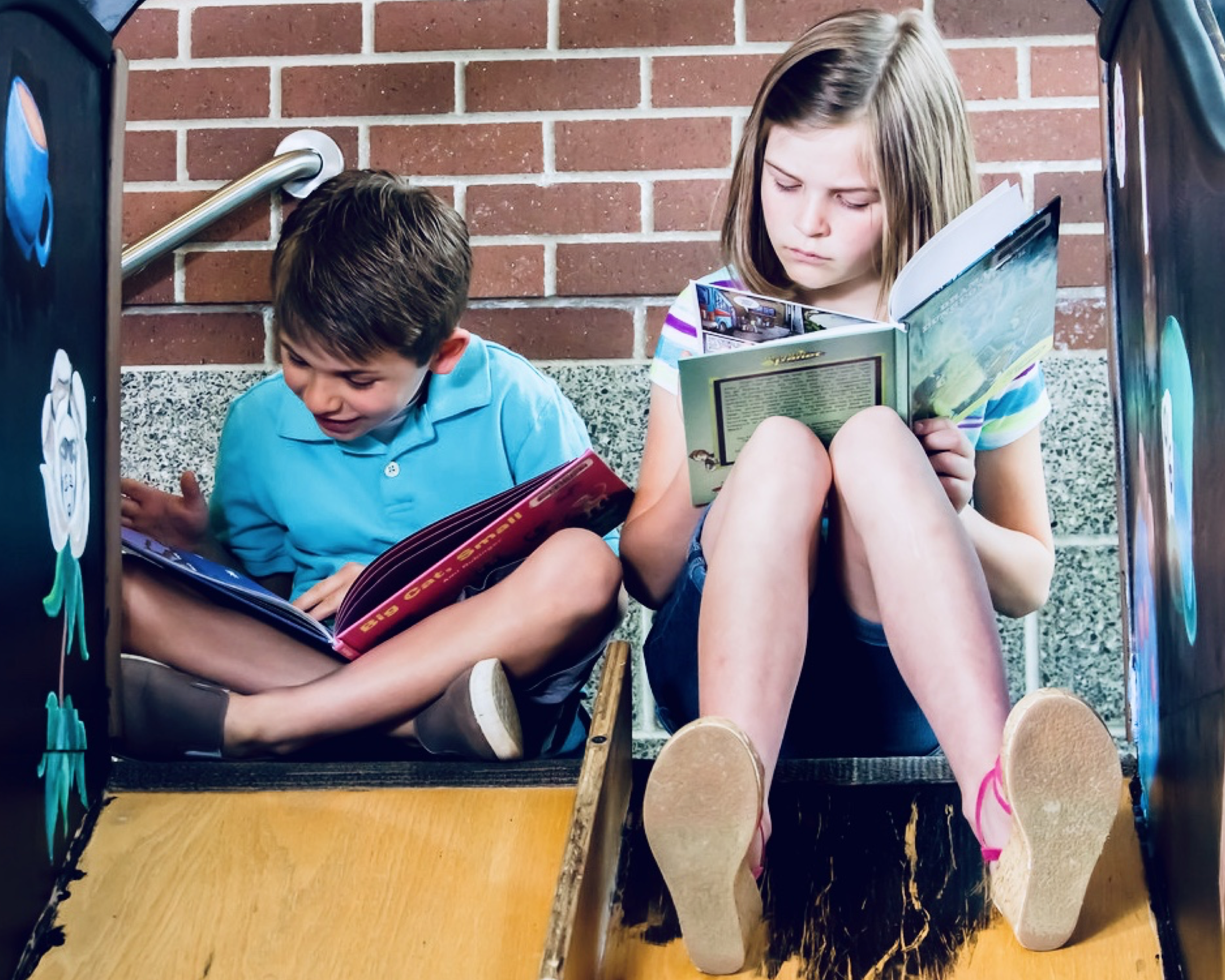 Kids reading books on a playground.