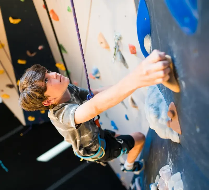 Climber scaling Mt. Van Hoevenberg's Indoor climbing wall during their bouldering competition.