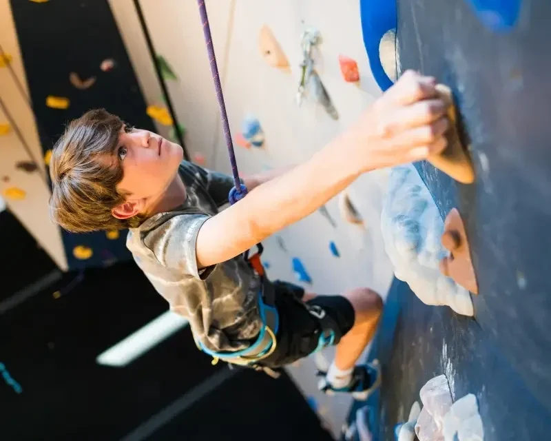 Boy competing in bouldering event at mt. van hoevenberg in lake placid.