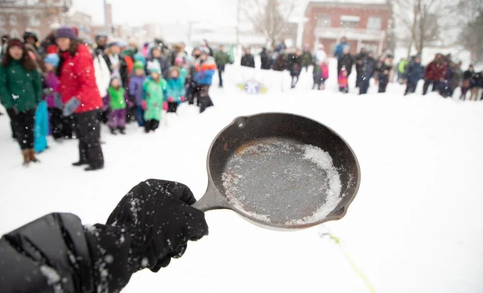Woman preparing to toss a frying pan at a winter carnival.