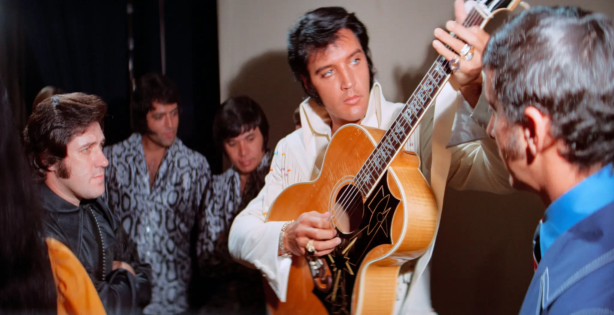 Elvis Presley playing guitar in a documentary featuring his live concerts.