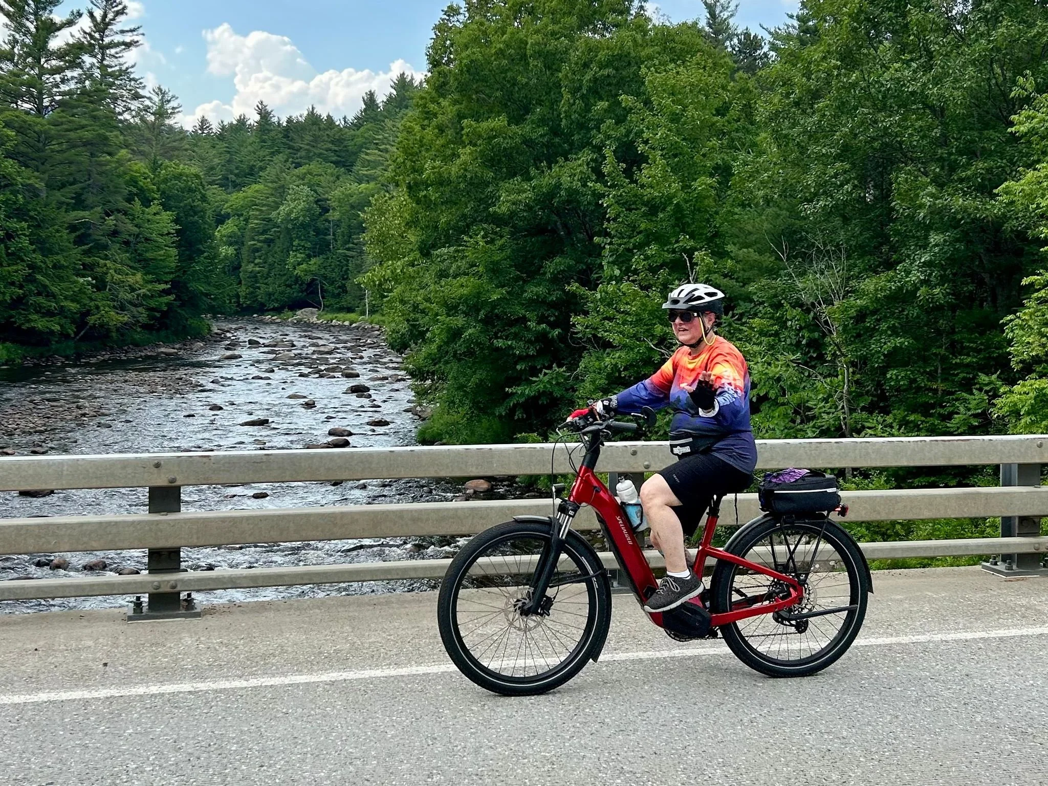 Cyclist on an ebike cruising on a bridge over the Ausable River.