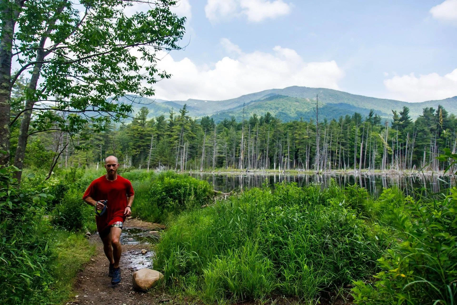 Man racing near whiteface mountain on nature trail near wetlands.
