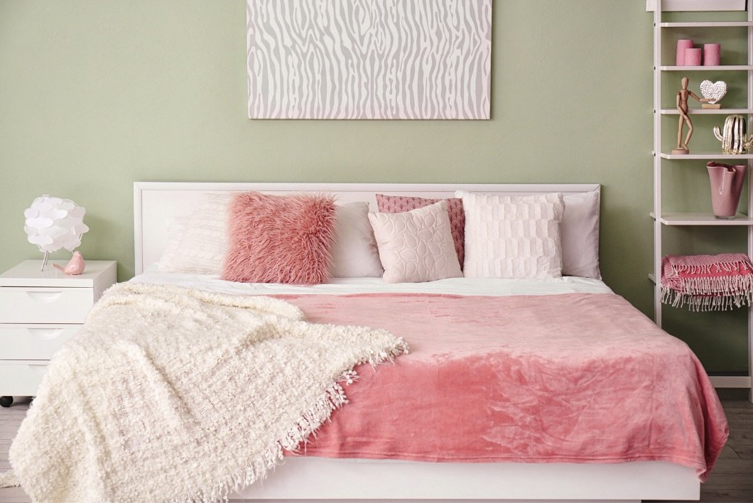 Décoration au dessus d'un lit avec édredon et coussin rose