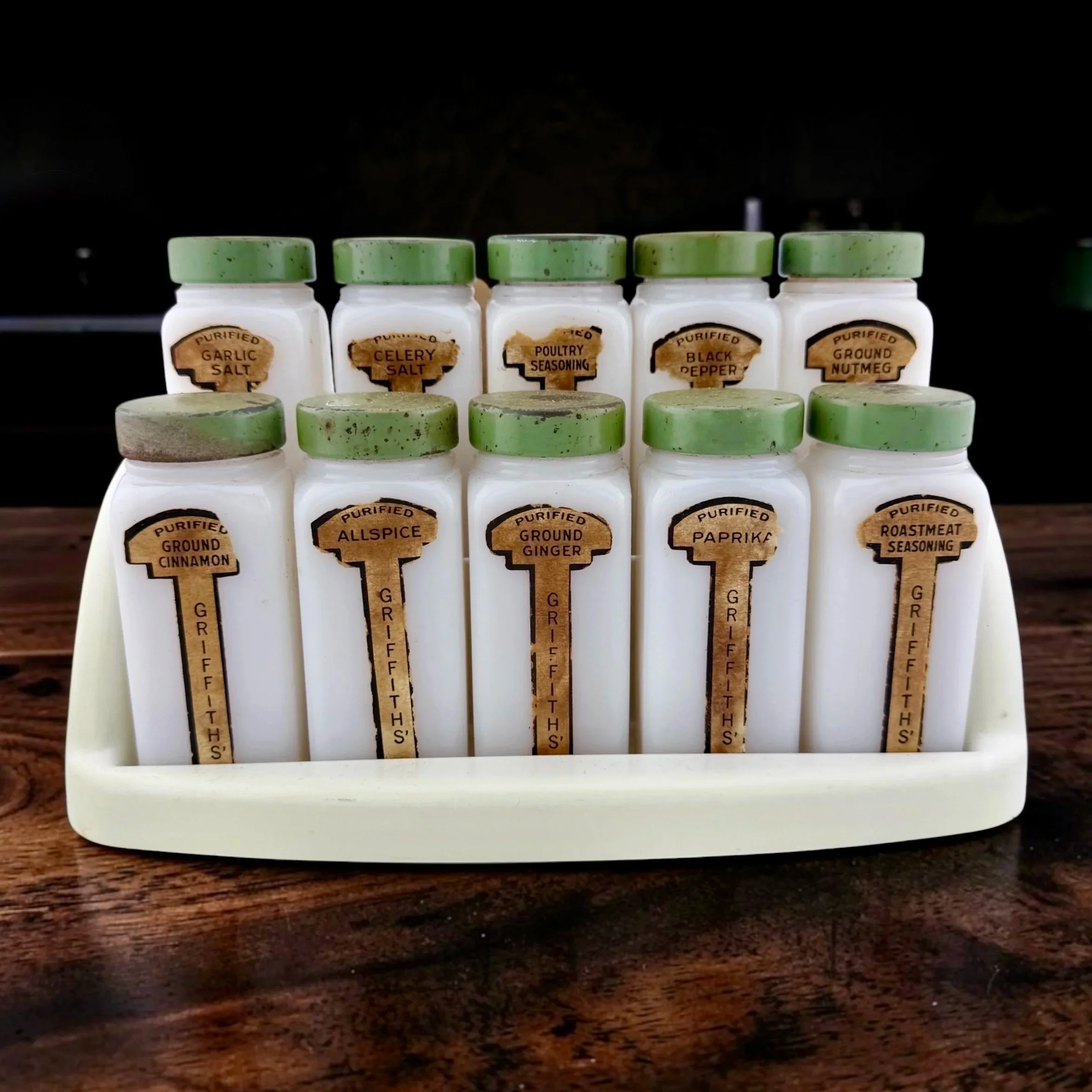 Vintage Griffith’s Milk Glass Spice Jar Set c. 1940s or 1950s, White milk glass rectangular shakers, green metal lids, paper labels, and a matching countertop or wall-mount holder