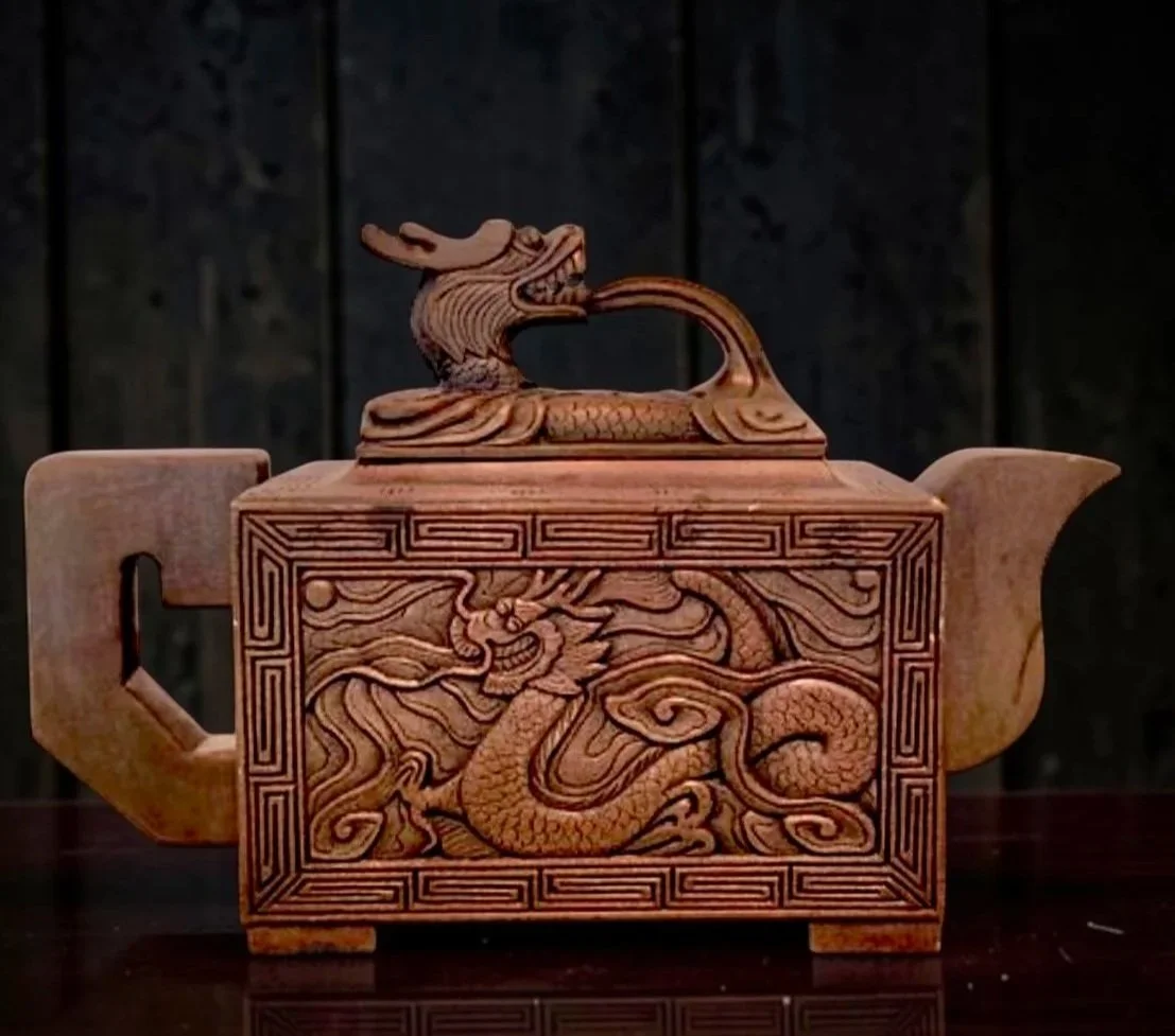 Ornate wooden teapot with carved dragon motif on the front, featuring a dragon head finial on the lid.