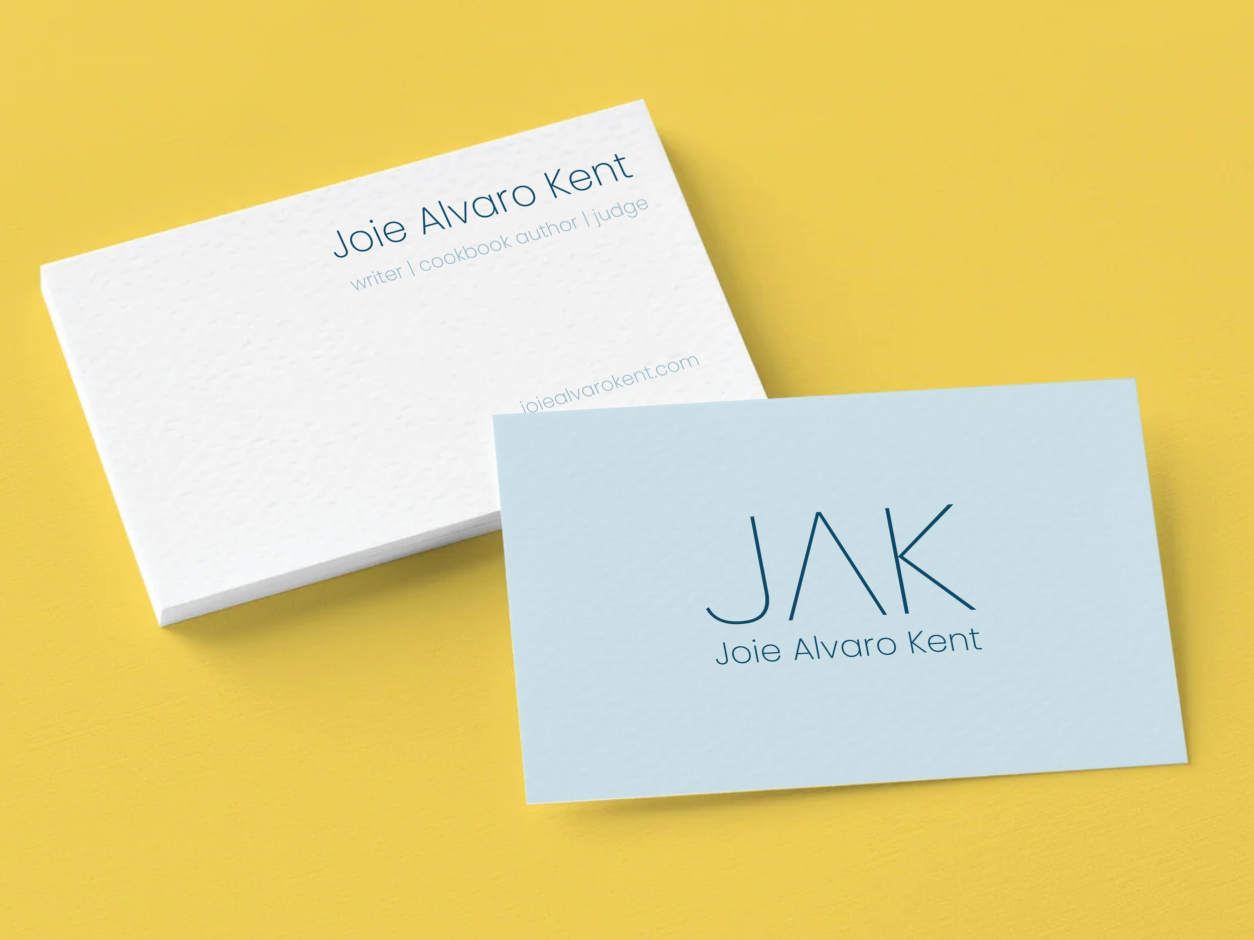 Applied Design: The business card utilizes the simple elegance of the monogram on premium, textured linen cardstock to present Joie Alvaro Kent with minimalist sophistication. Bathed in soft, muted West Coast shades of blue, the layout balances the u