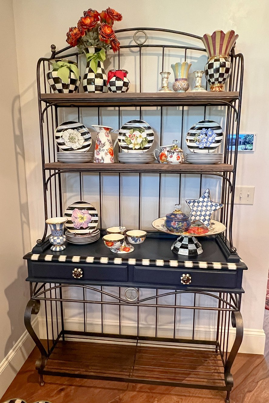 Decorative hutch with checkered and floral ceramic vases, plates, and bowls.
