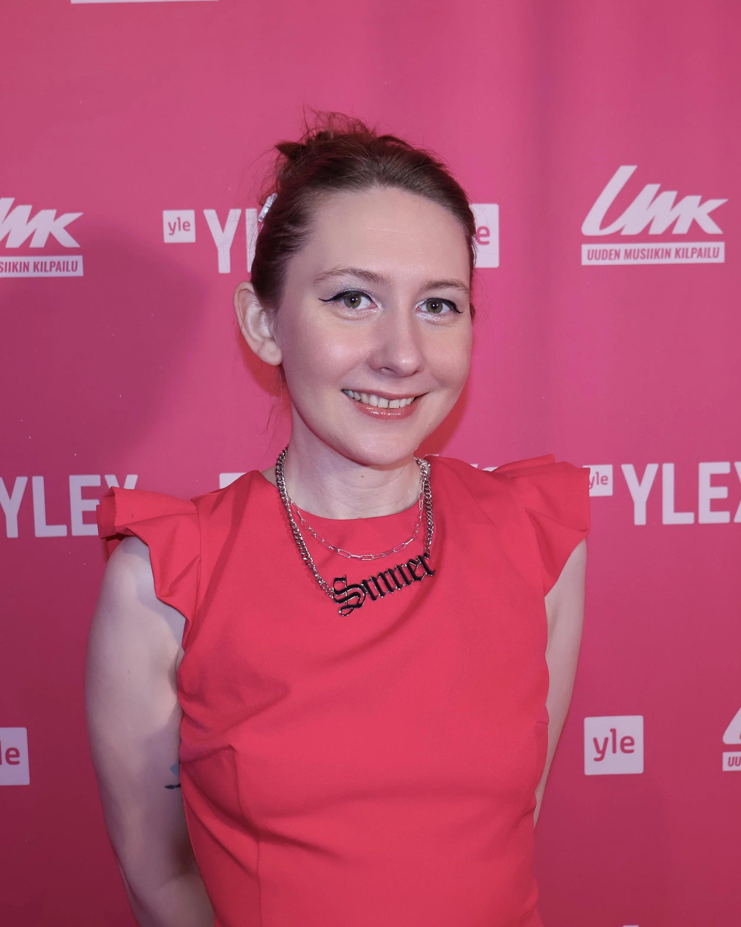 A portrait photo of Renata standing in front of a background with the text "Yle" and "UMK Uuden Musiikin Kilpailu"
