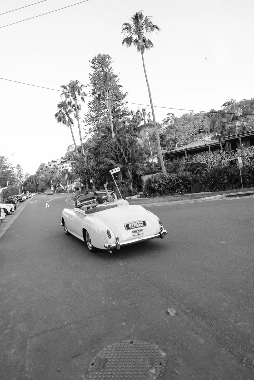 Bride and groom driving away in a car on their way to the reception at Dunes Palm Beach