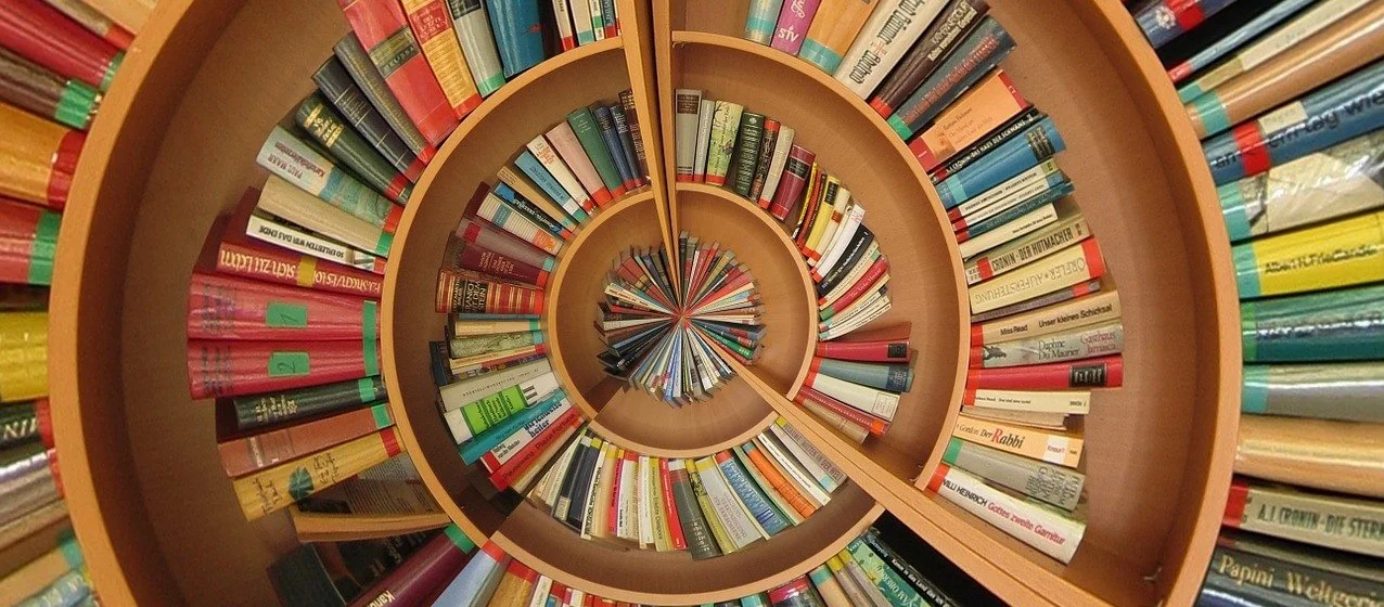 A spiral staircase designed as a bookshelf filled with colorful books.
