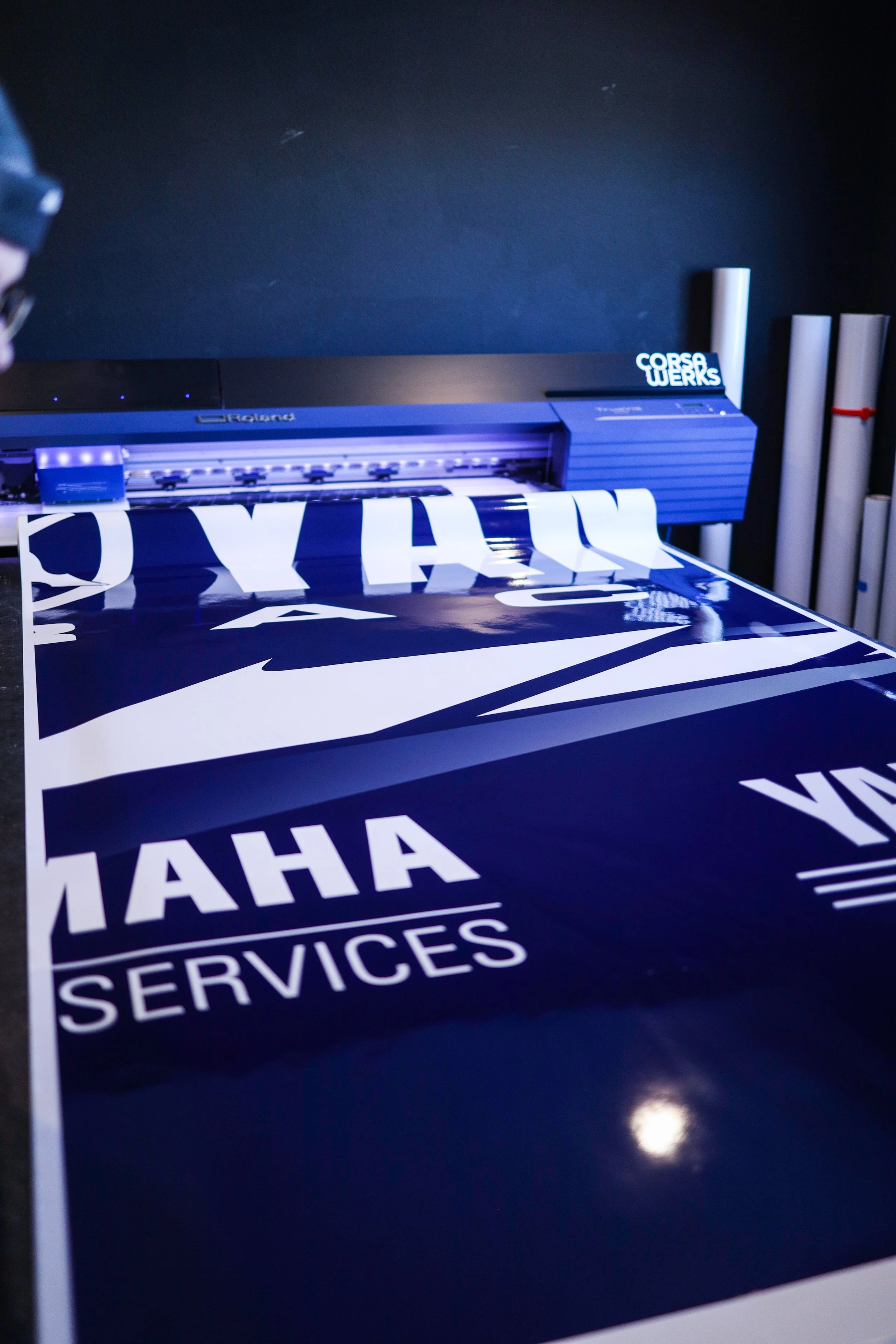 Printing large signage using a state-of-the-art printer, with blue and white graphics and the logo "HAHA SERVICES" visible on the material.