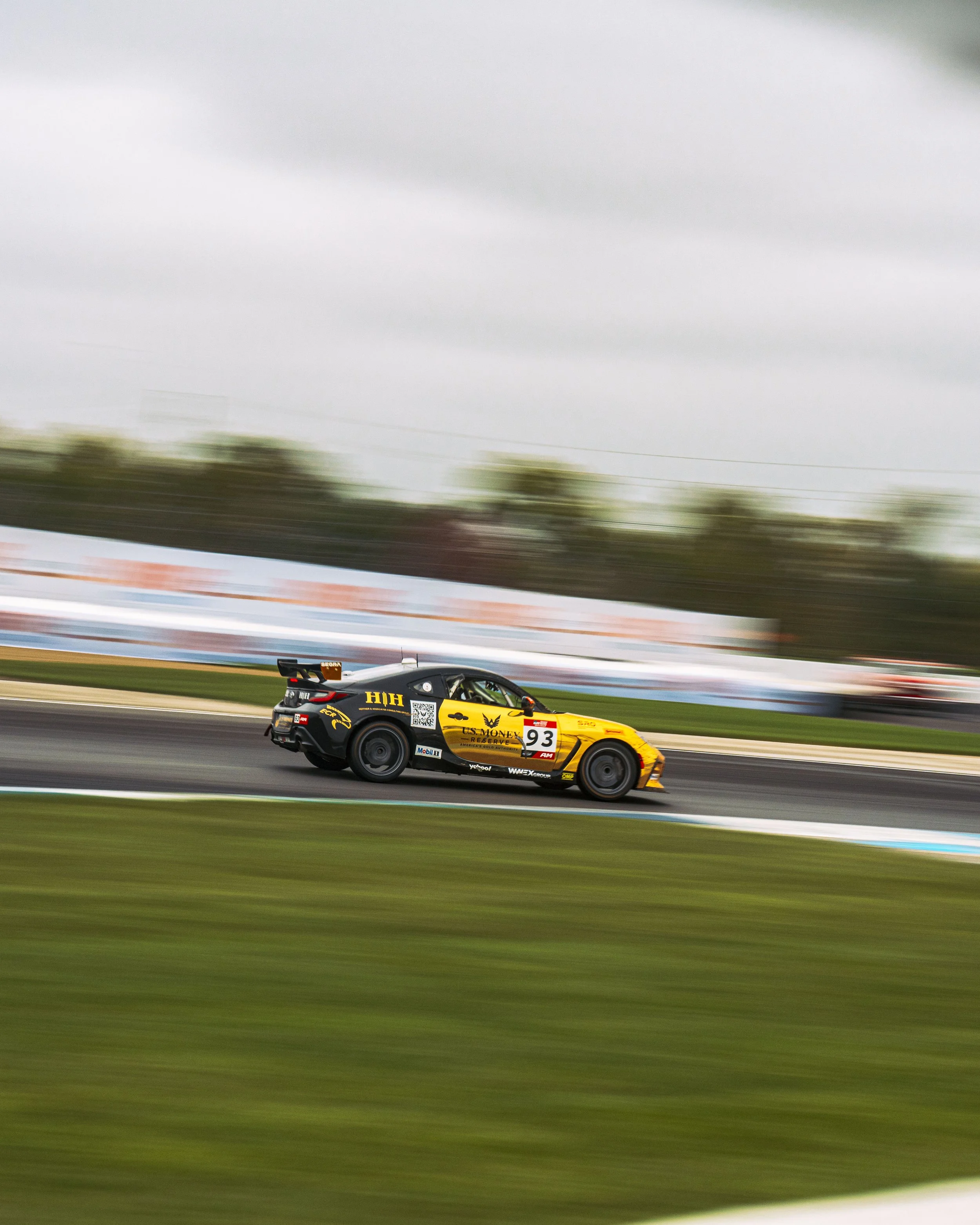 A yellow and black race car speeding on a track with motion blur in the background.