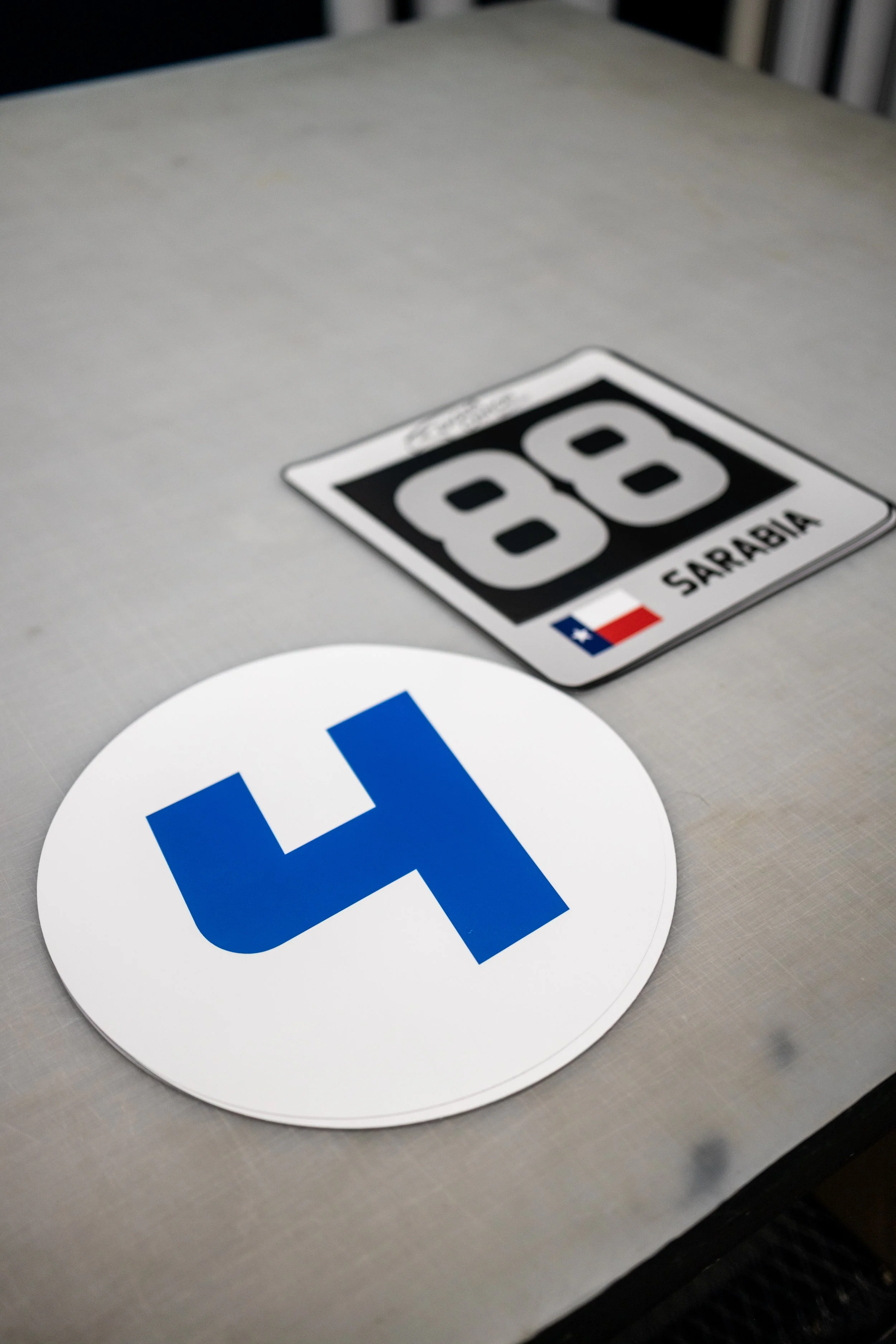 A large blue number 4 on a circular white background and a Texas road sign with the number 88 and the name Sarabia on it.