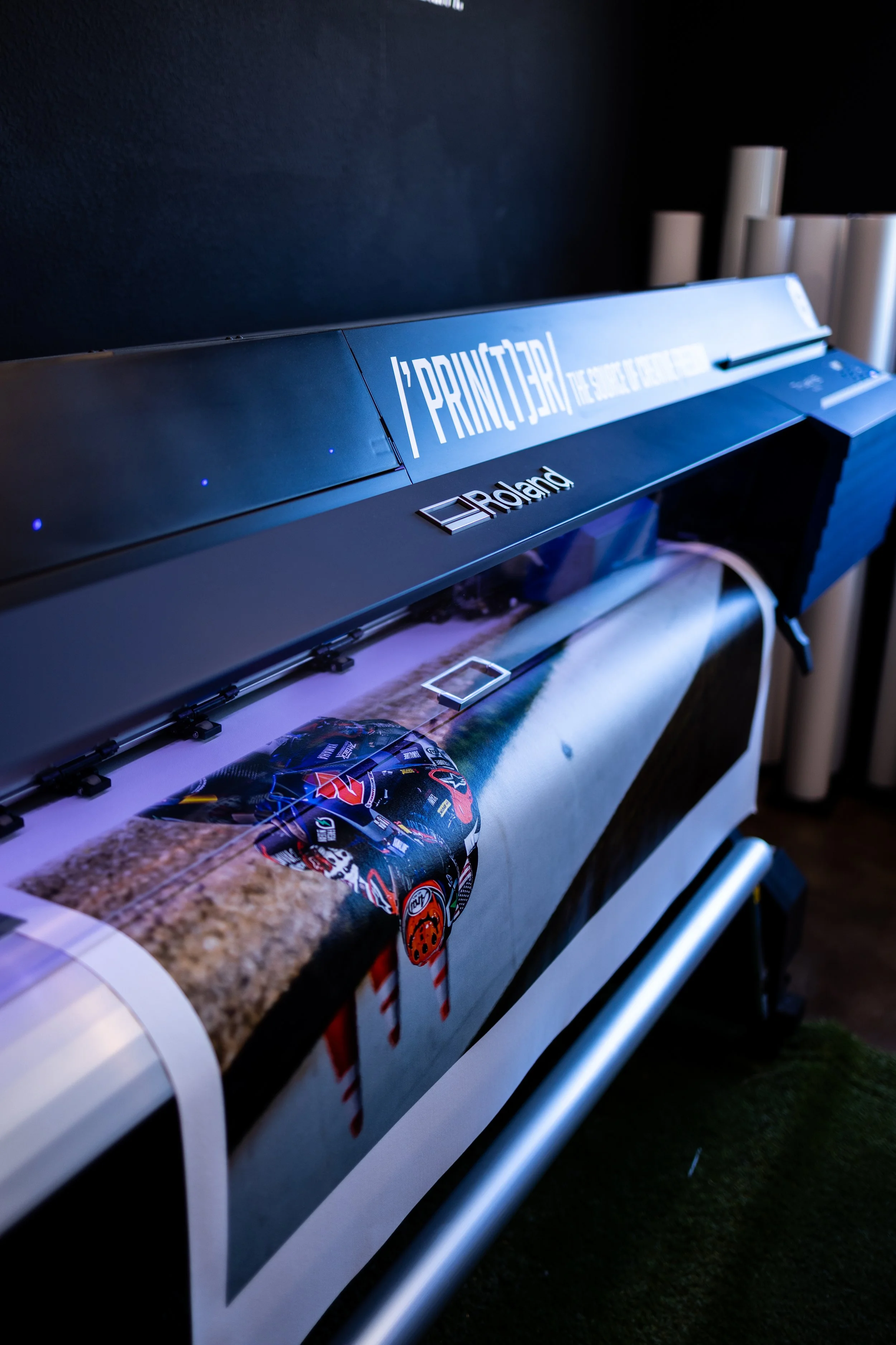 A large format printer printing a photograph of a racing car on fabric.