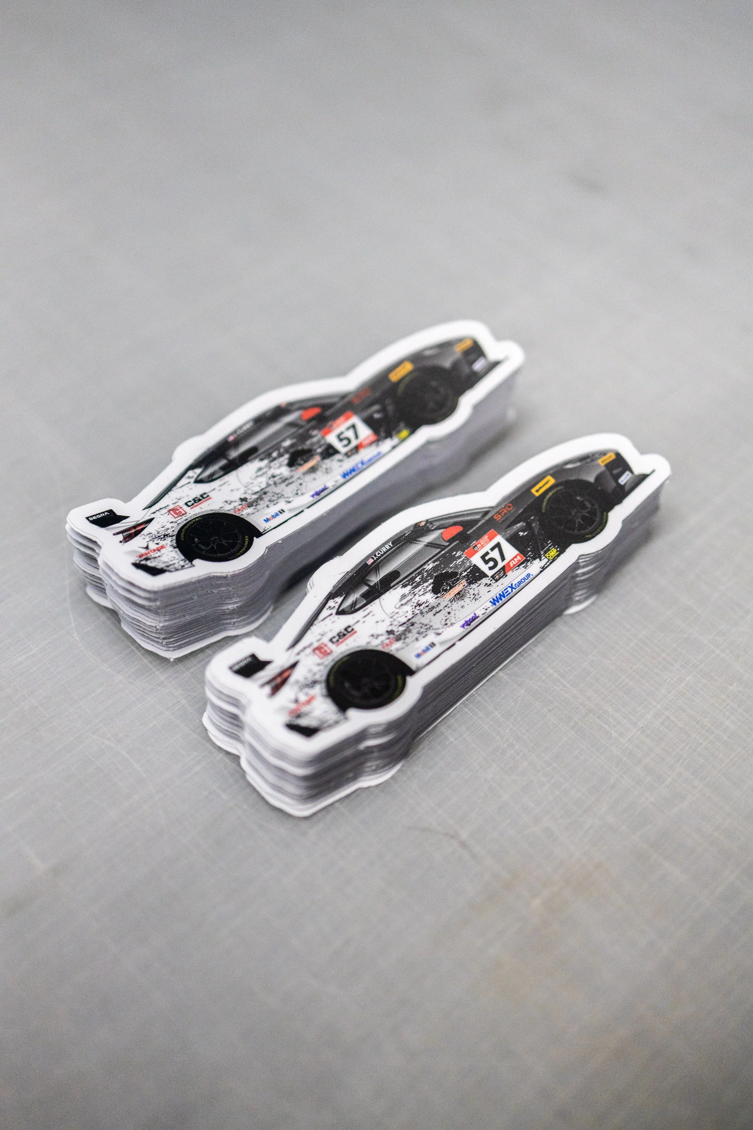 Stacks of car-themed stickers featuring a race car with the number 57, placed on a light gray surface.